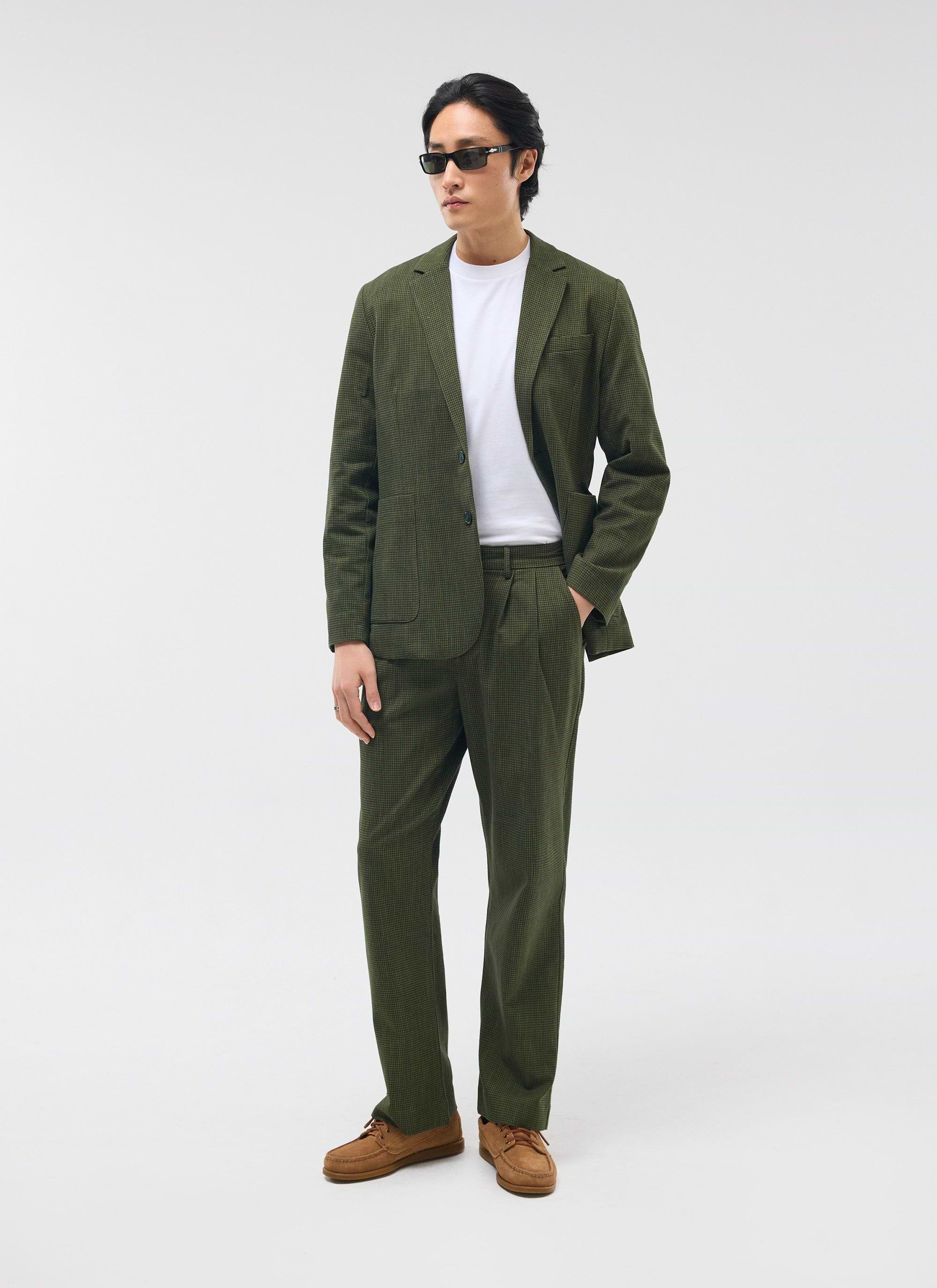 A man models the Percival forest green micro check suit, featuring the Pleated Tailored Trousers, styled with a white tee.