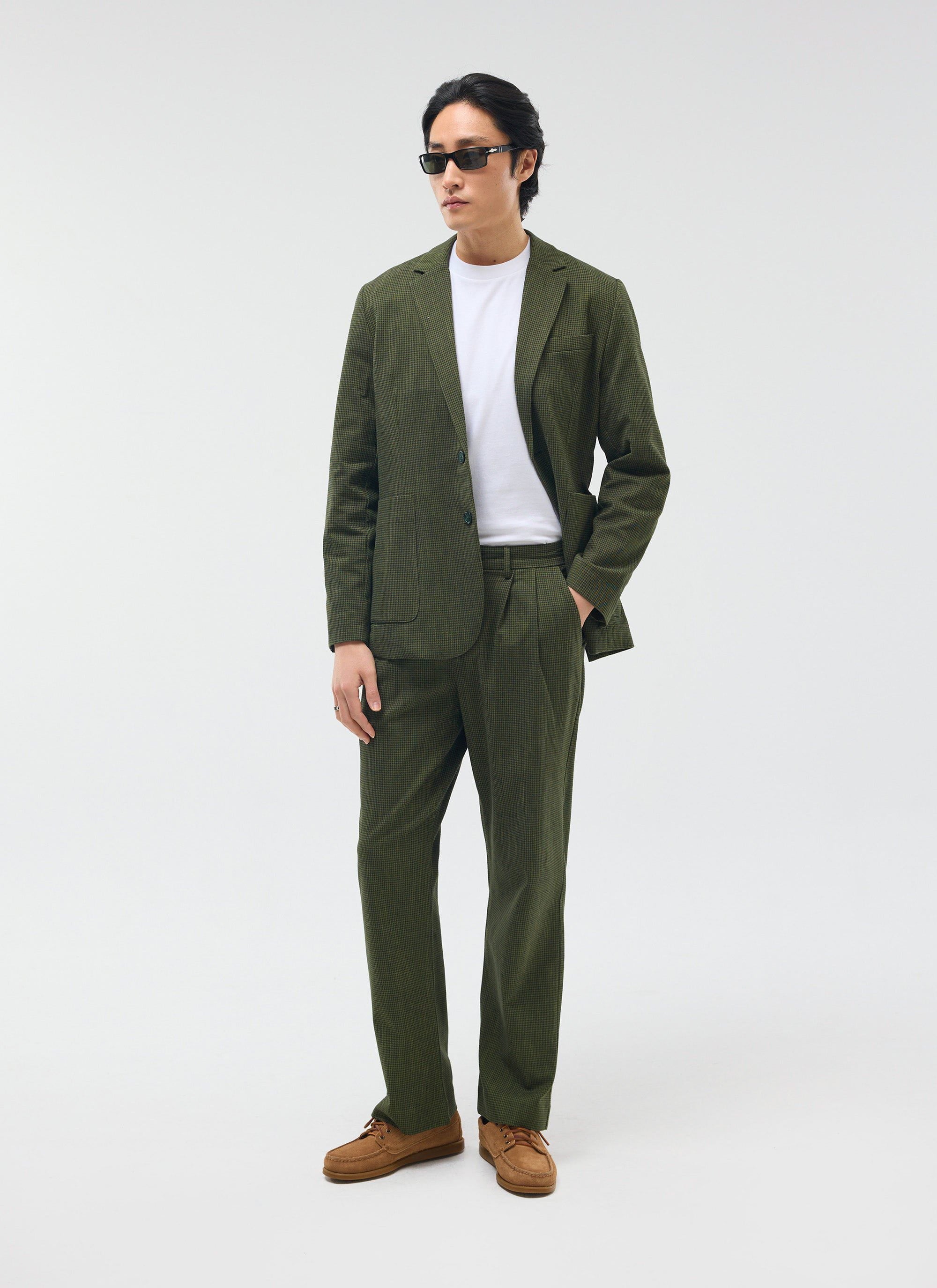 A man models the Percival forest green micro check suit, featuring the Pleated Tailored Trousers, styled with a white tee.