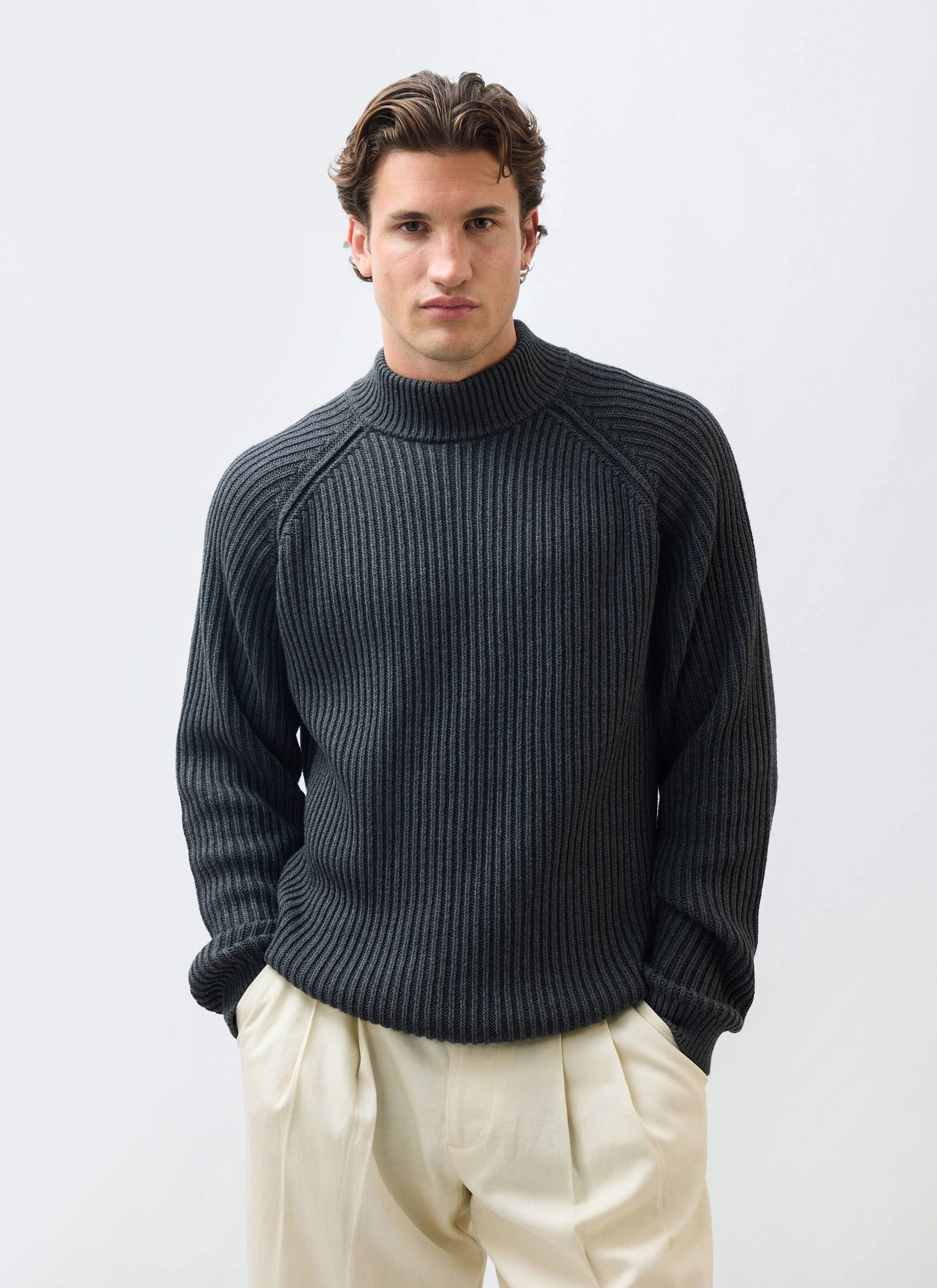 A model wears the Percival Library Turtle Neck in charcoal, a ribbed cotton-wool blend jumper, styled with cream trousers.