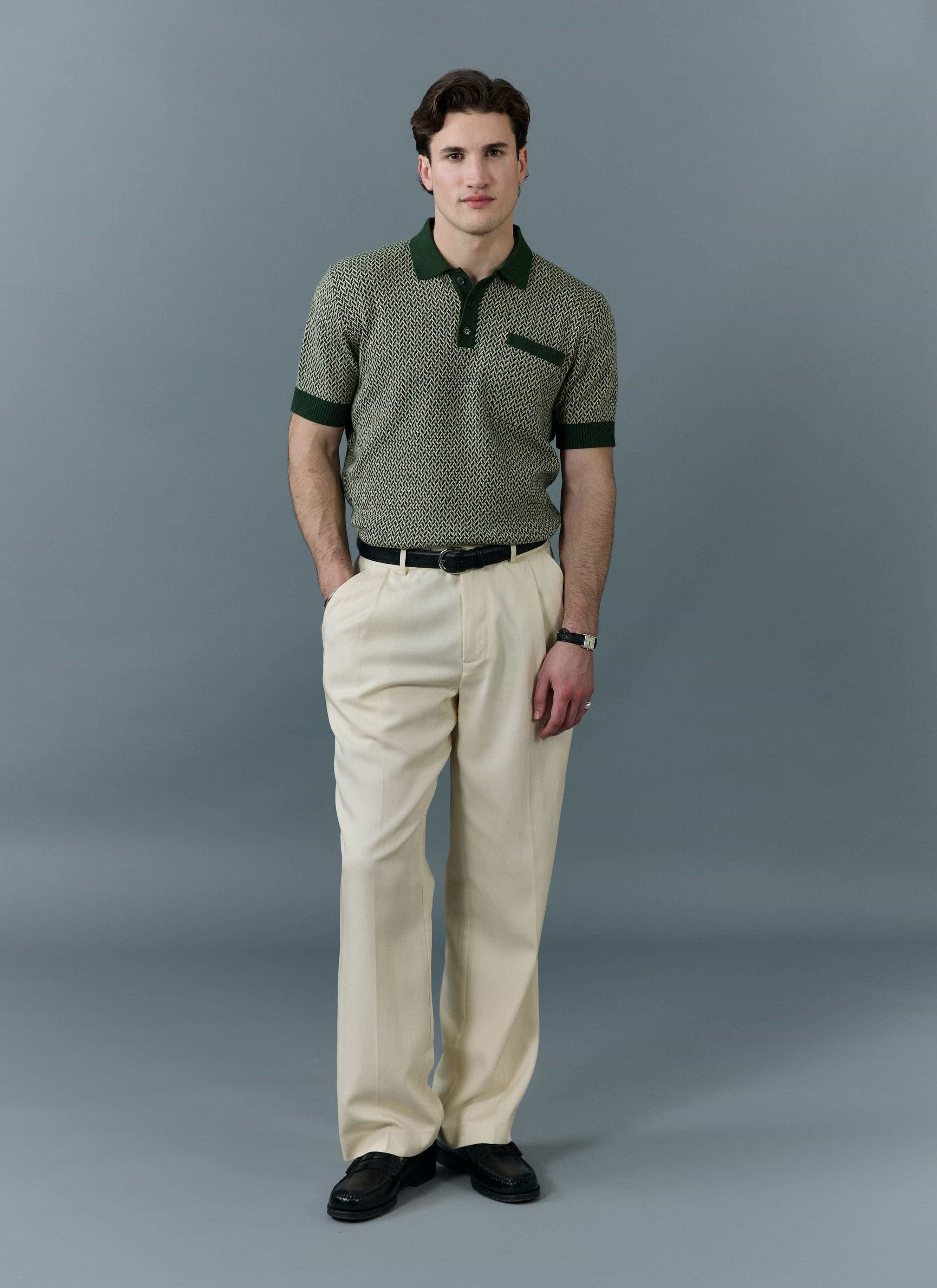 A male model wears the forest green Casa Martini knitted polo shirt from Percival with cream trousers and black loafers.