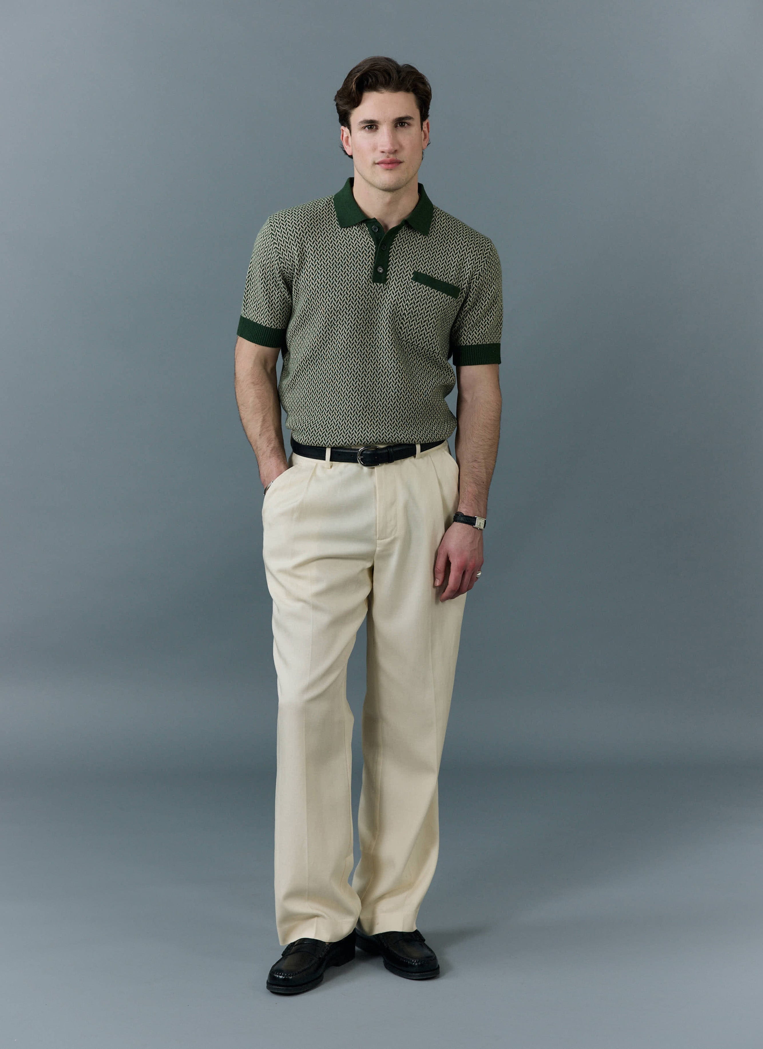 A male model wears the forest green Casa Martini knitted polo shirt from Percival with cream trousers and black loafers.