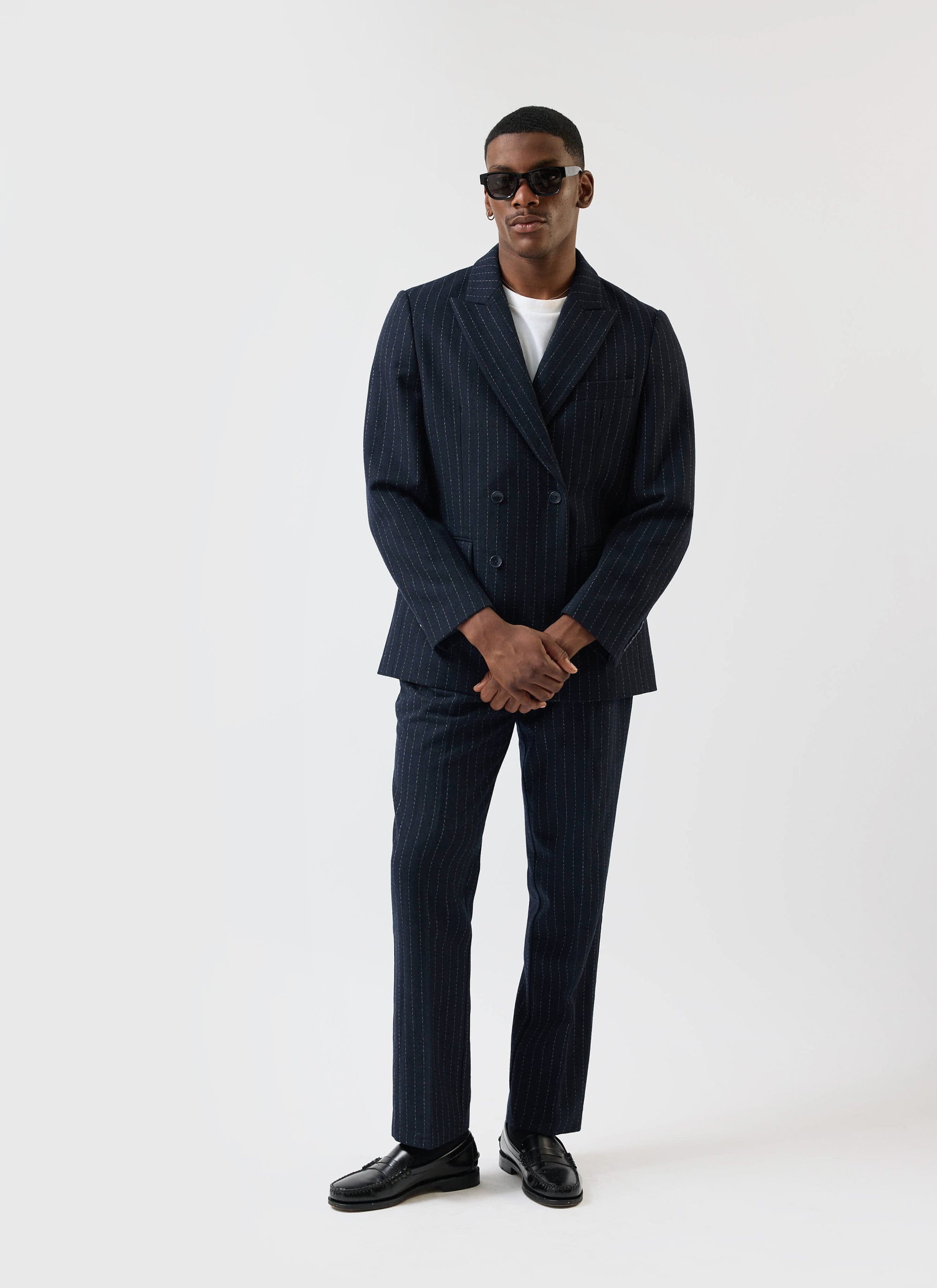 A model wears the Percival Textured Stripe suit in navy, featuring a double-breasted blazer and matching pleated trousers.