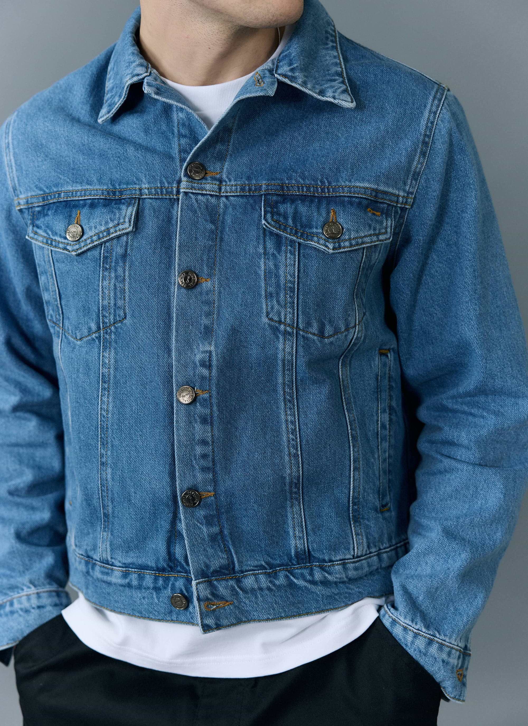 A close-up of a man modelling the light wash blue Western Trucker Jacket from Percival over a white t-shirt.