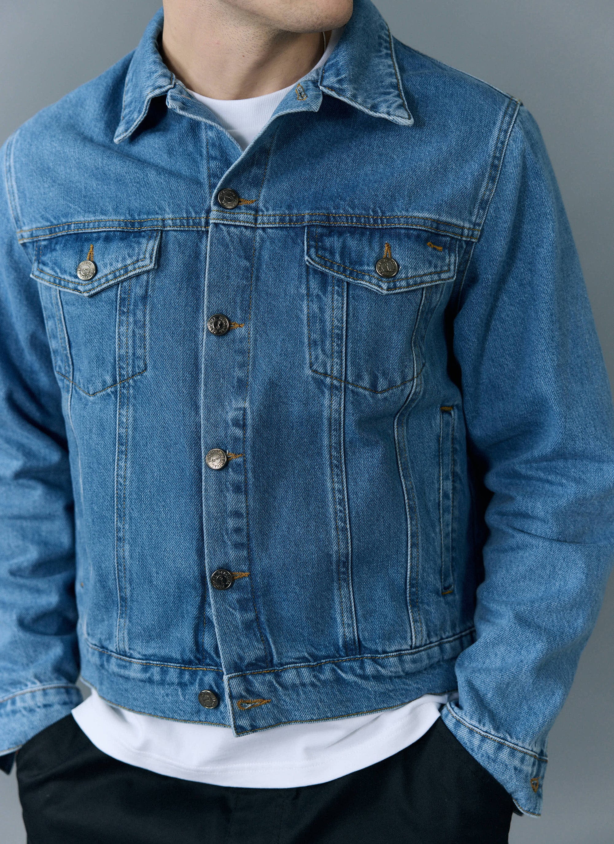 A close-up of a man modelling the light wash blue Western Trucker Jacket from Percival over a white t-shirt.