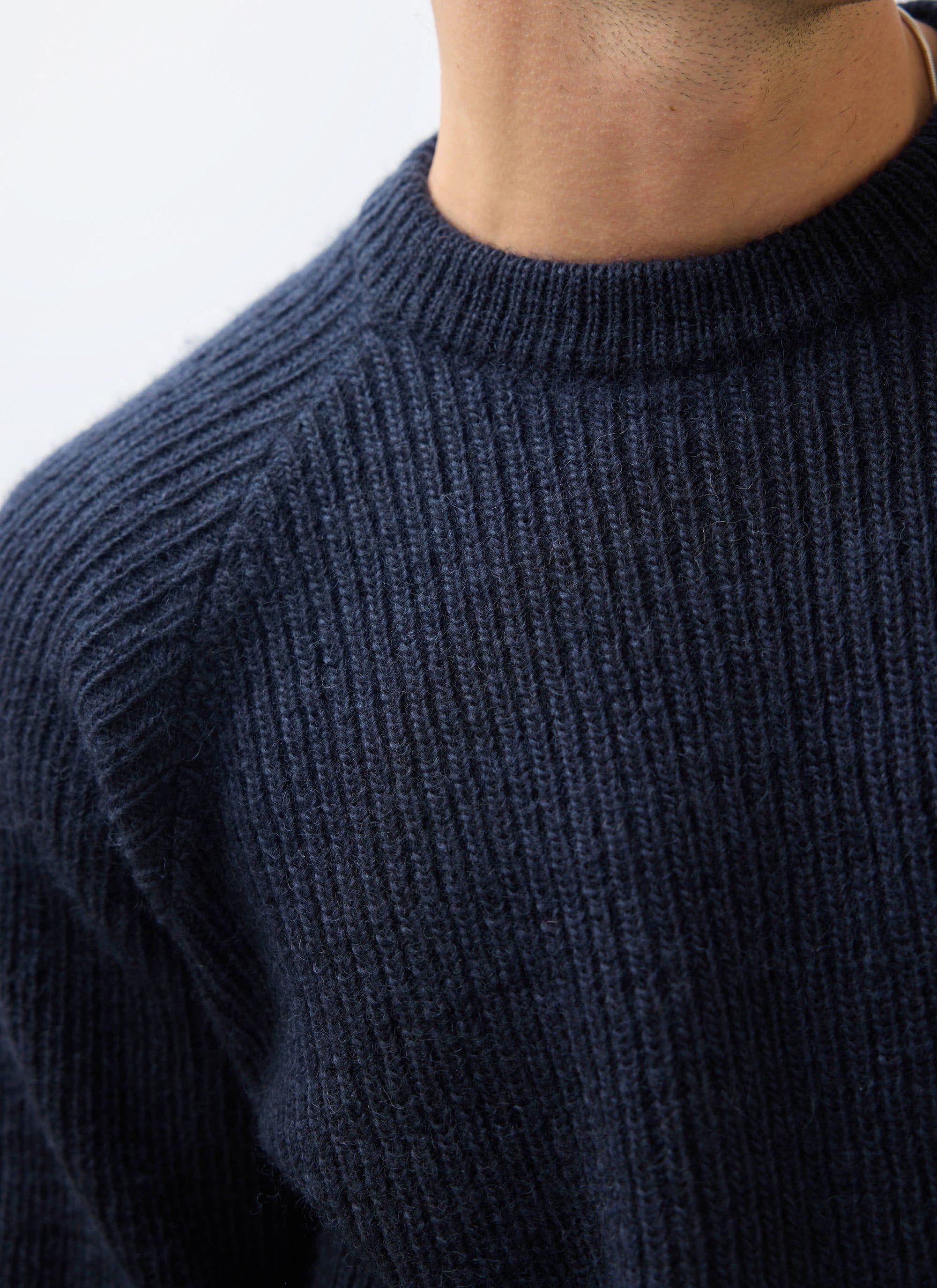 A close-up of the chunky ribbed knit and raglan sleeve detail on the navy wool Fisherman Jumper from Percival.