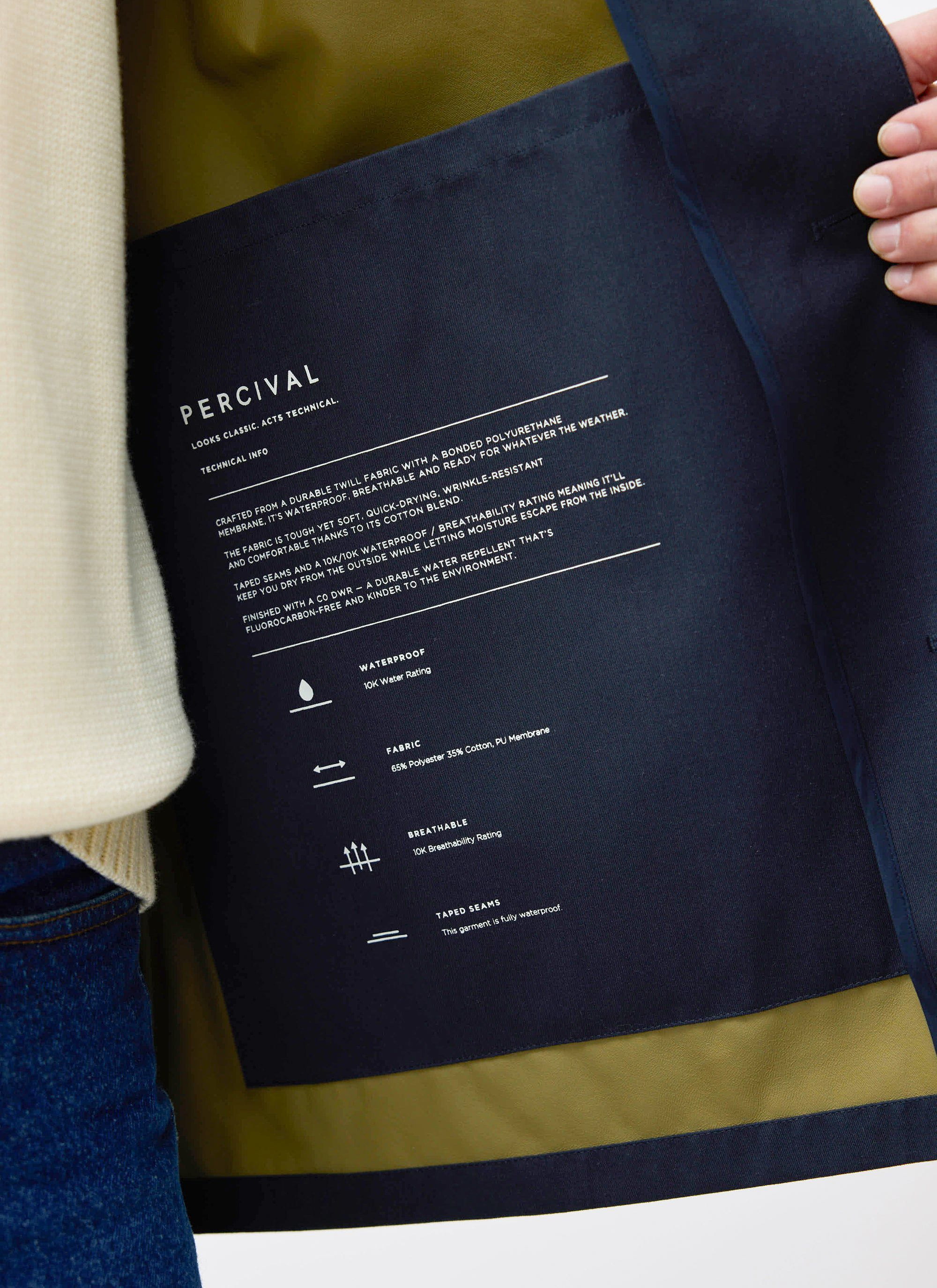Close-up of technical details and branding on the interior of the Percival Sherlock Short Trench Coat in midnight.