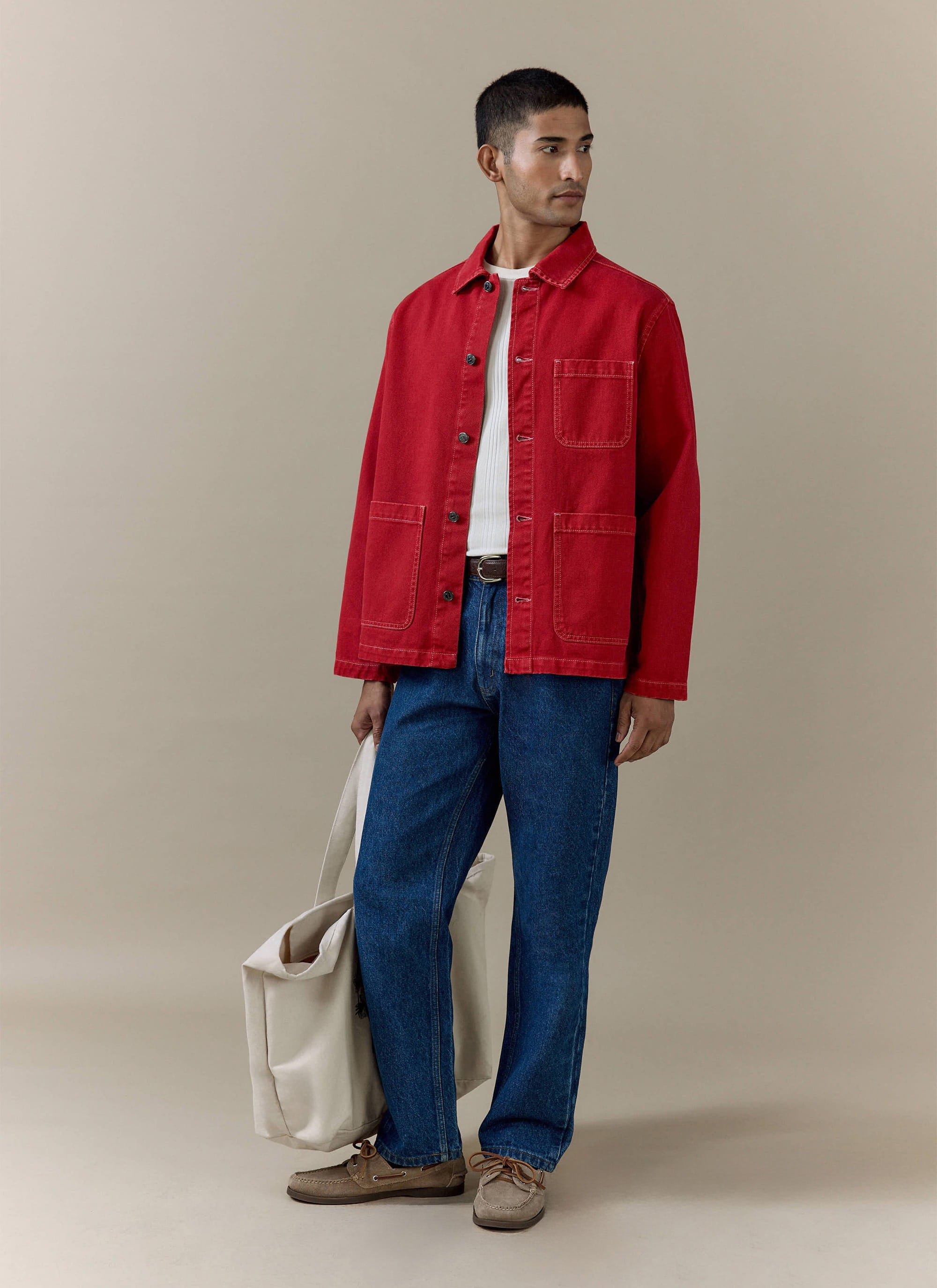 Red cotton canvas Percival Oliver Chore Jacket styled on a model with blue jeans and a cream tote bag.