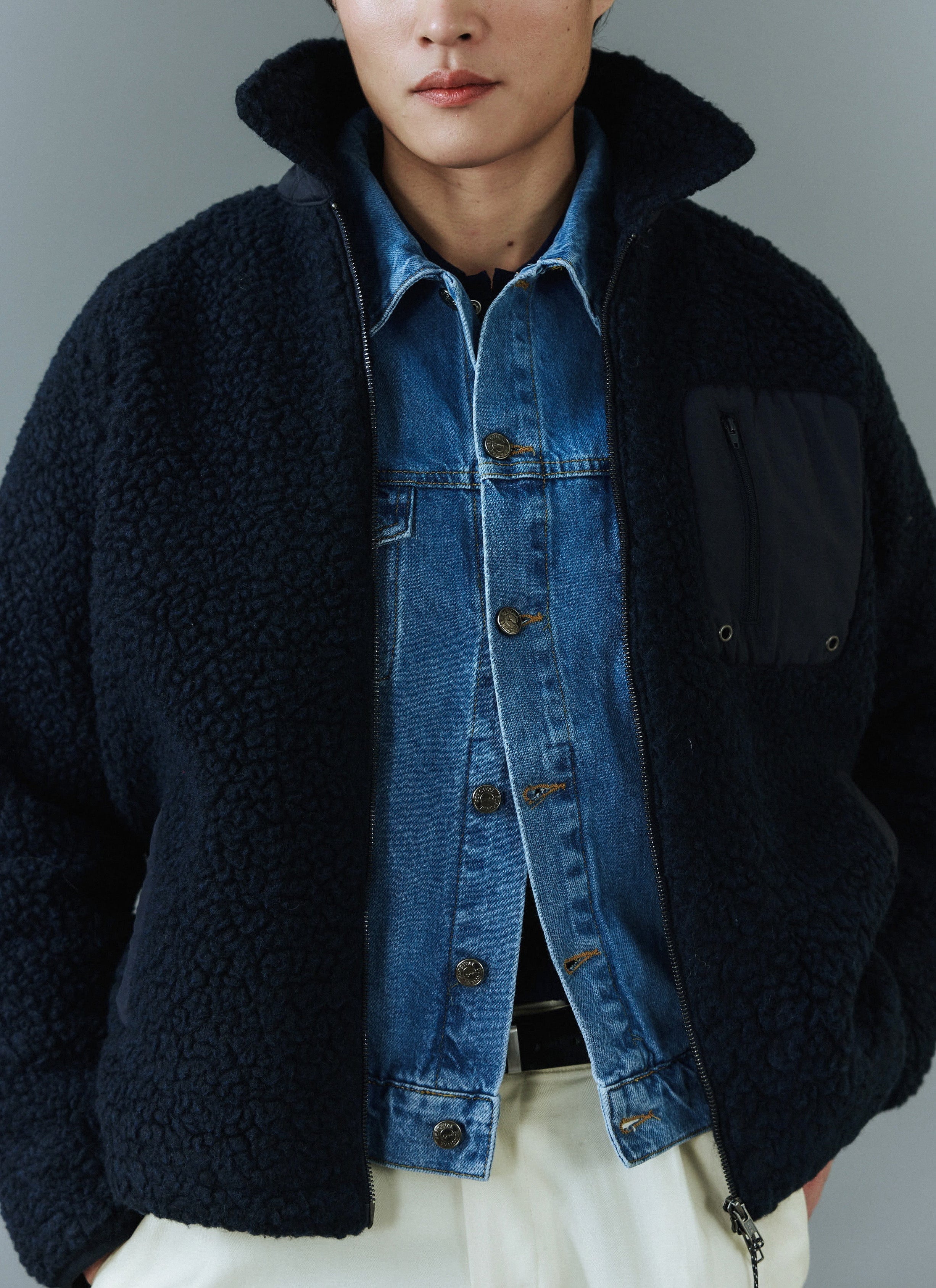 A model wears the Percival navy wool fleece jacket layered over the light wash blue denim trucker jacket.