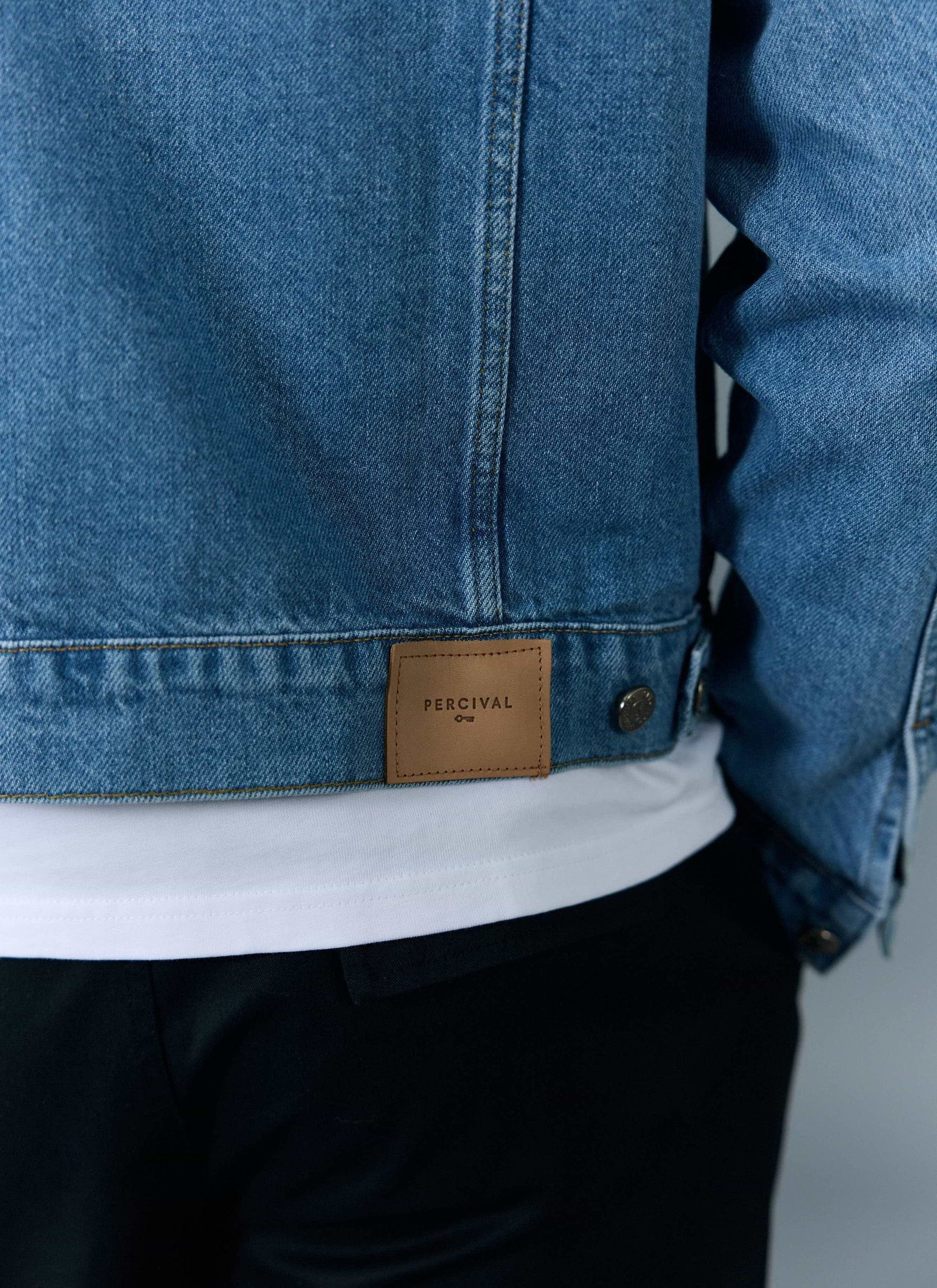 A close-up of the back of the Percival Western Trucker Jacket in light wash blue denim, showing the brown leather patch.