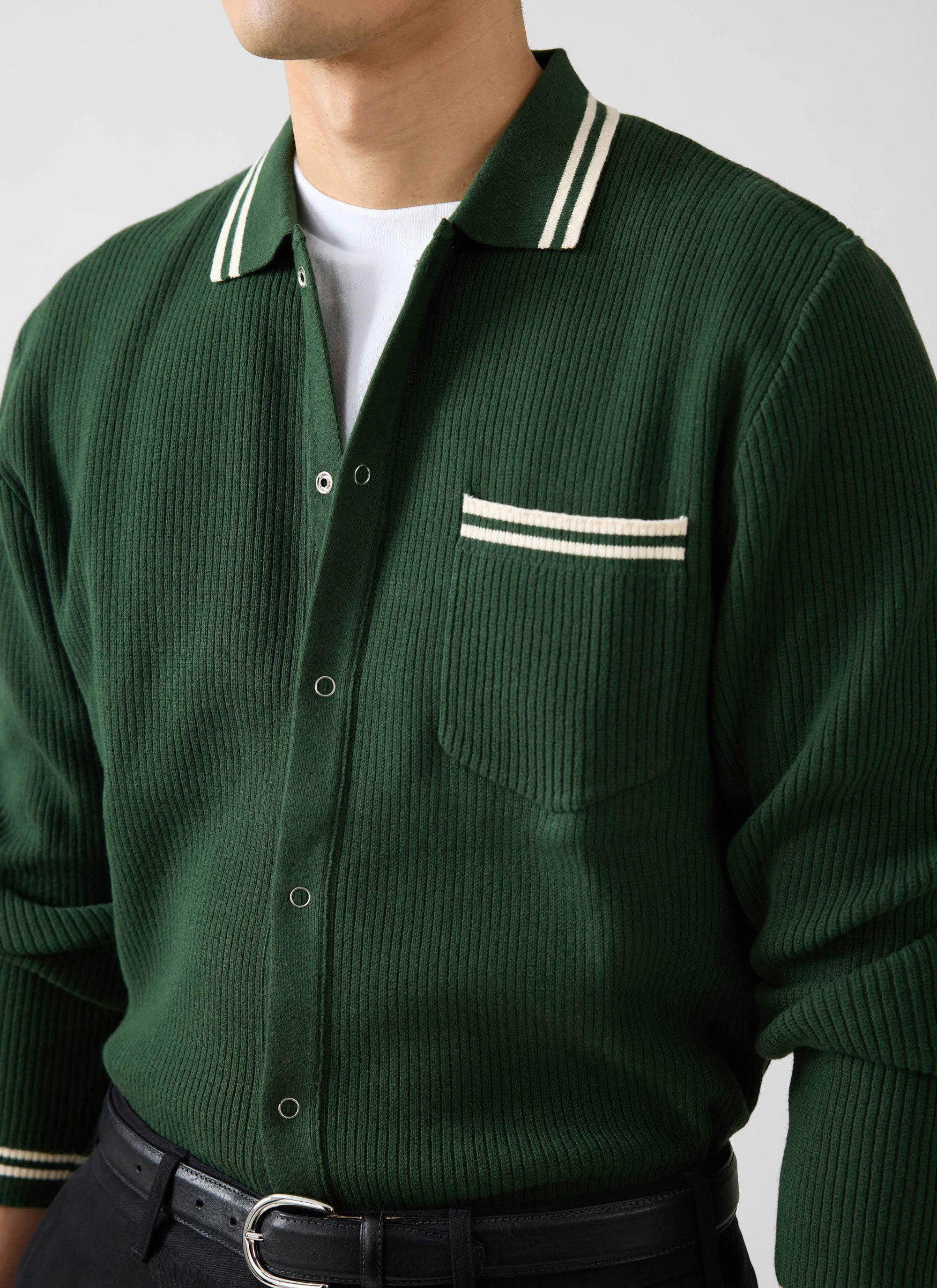 Close-up of a model wearing the Percival Pablo forest green knitted shirt with white striped collar and pocket detail.