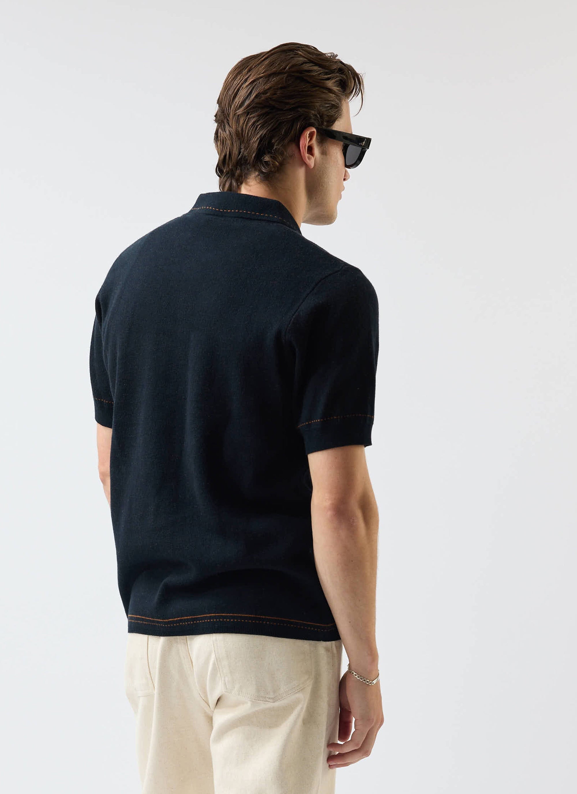 A model, seen from behind, wears the Percival Folio Knitted Shirt in dark navy with tobacco stitching detail.