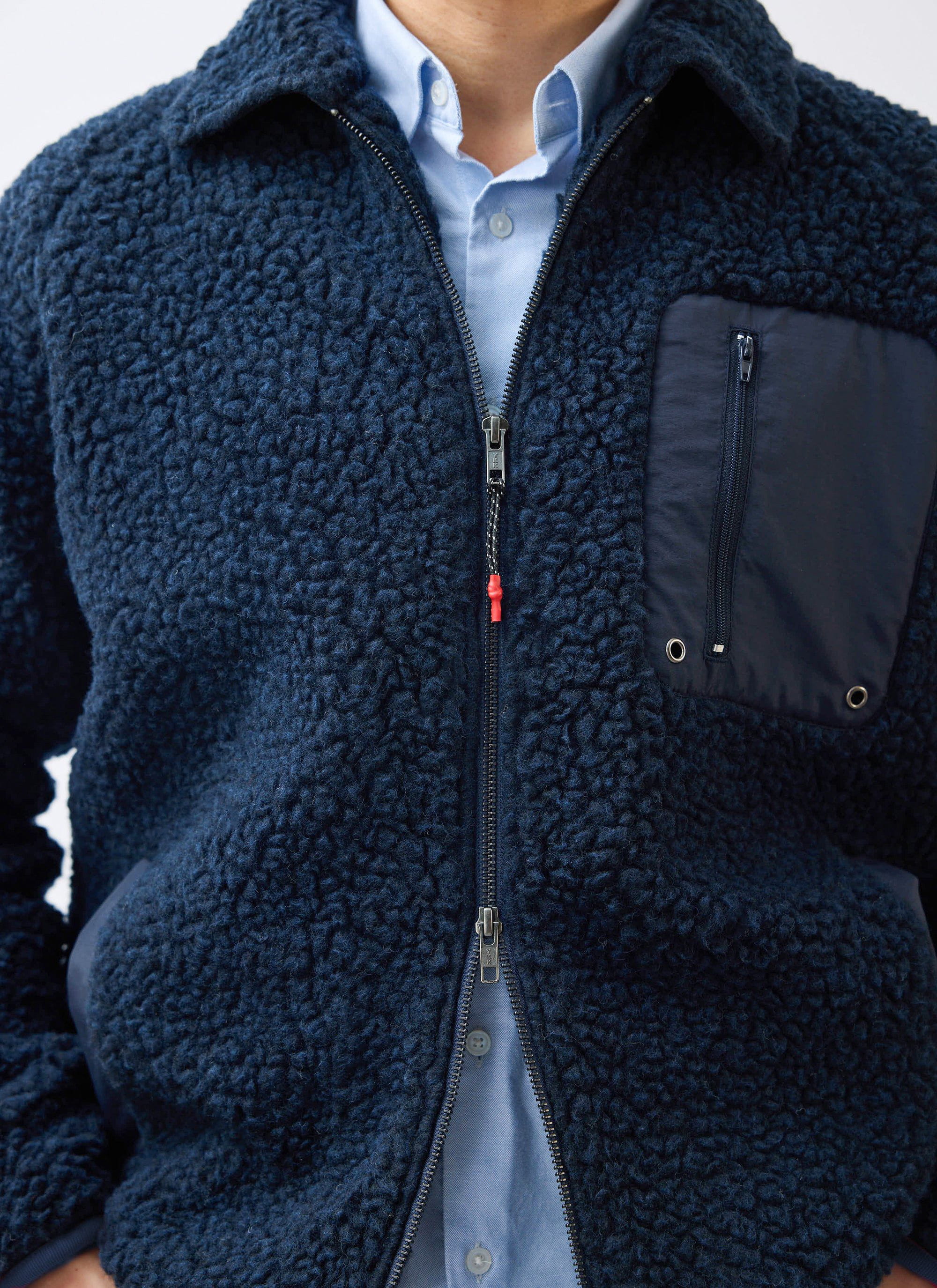 Close up of the navy wool fleece jacket by Percival with zip and pocket detail, worn over a blue shirt.