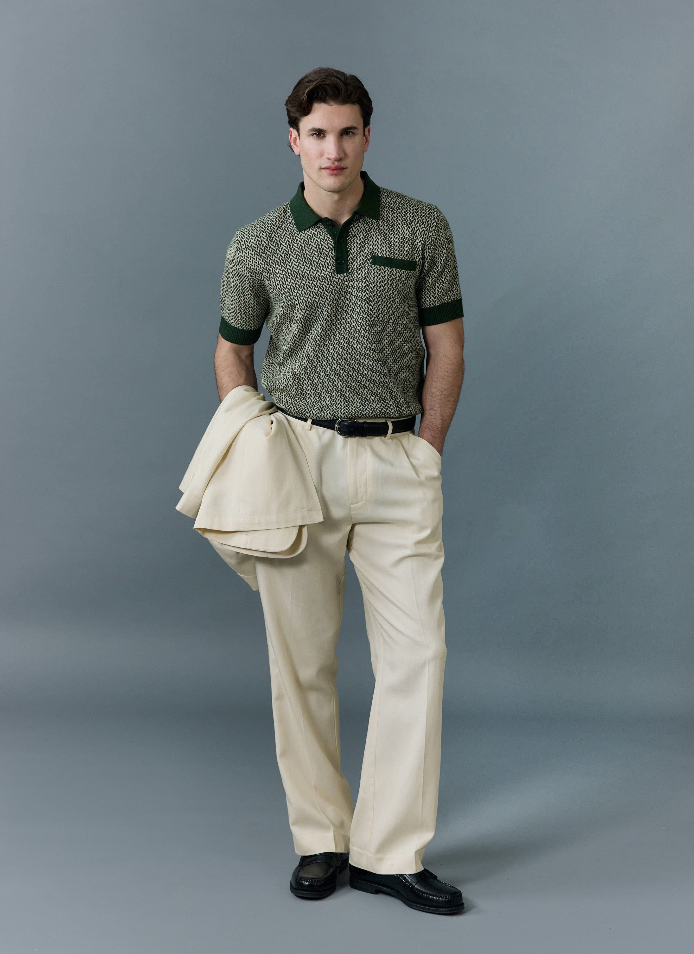 A model wears the Percival Casa Martini knitted polo in forest green with cream trousers, holding a matching cream jacket.