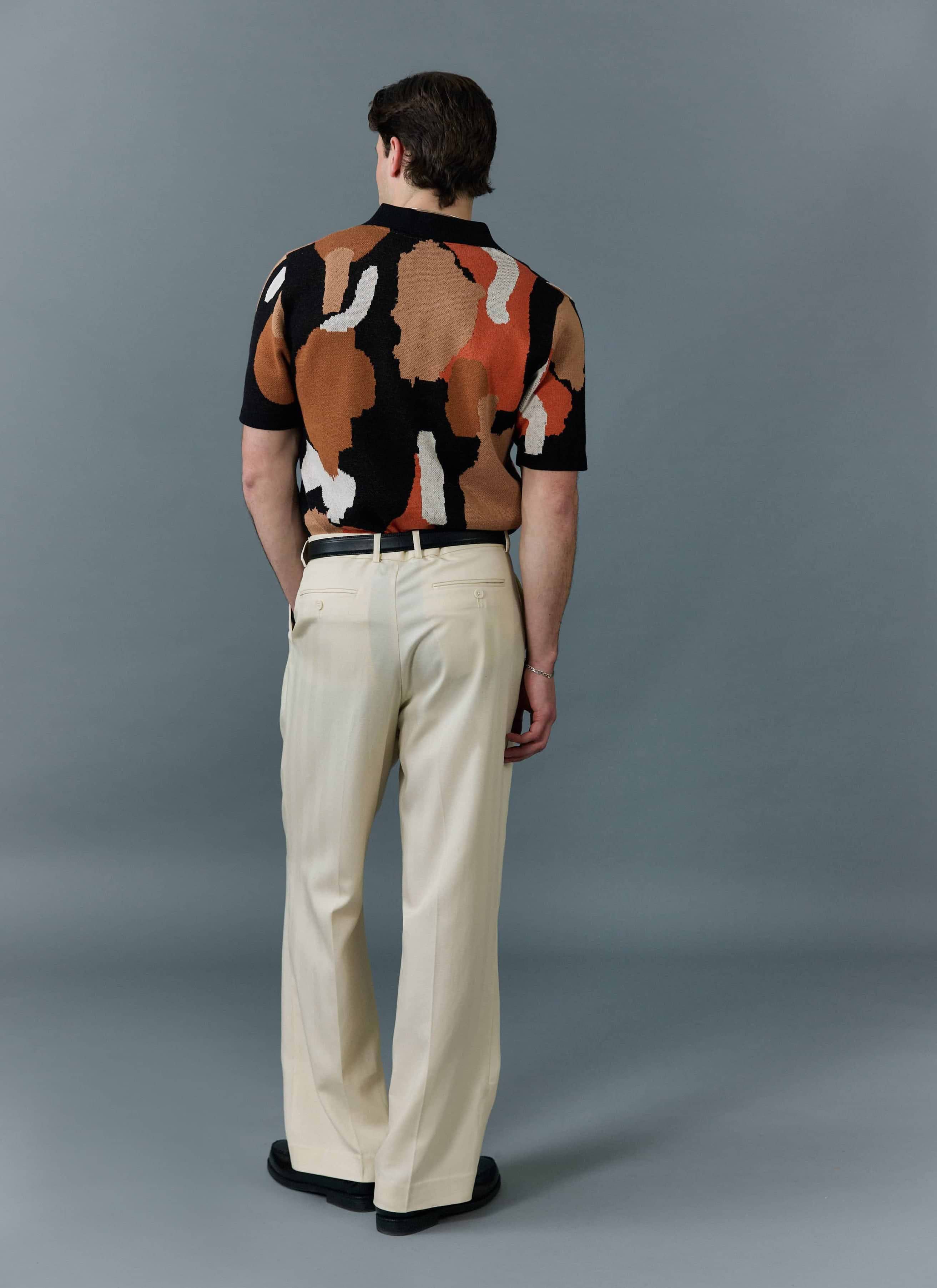 A man photographed from behind wearing the Percival Impressionist Jacquard knitted shirt with cream trousers.