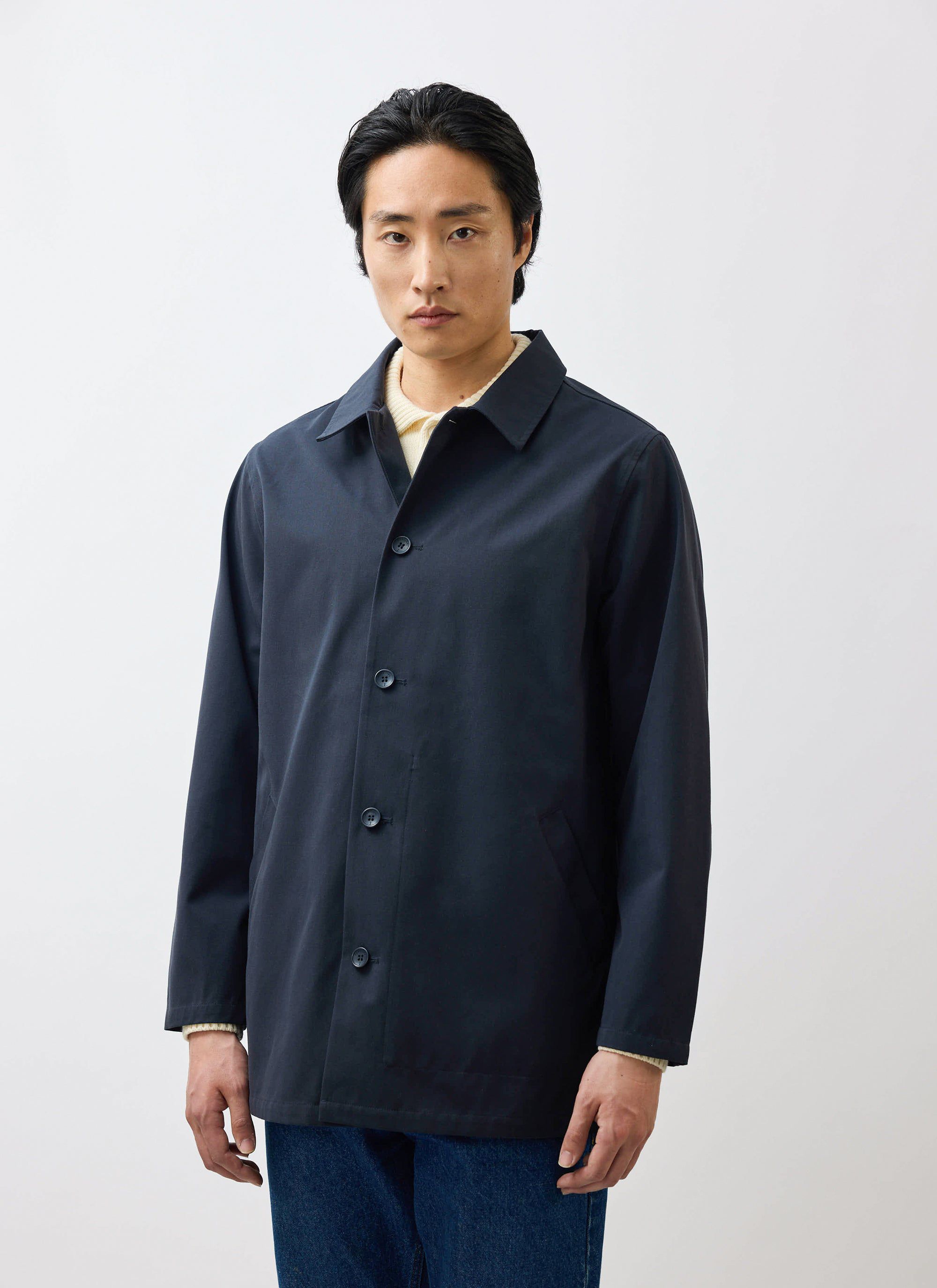 A model wearing the waterproof Sherlock Short Trench Coat in midnight navy by Percival.