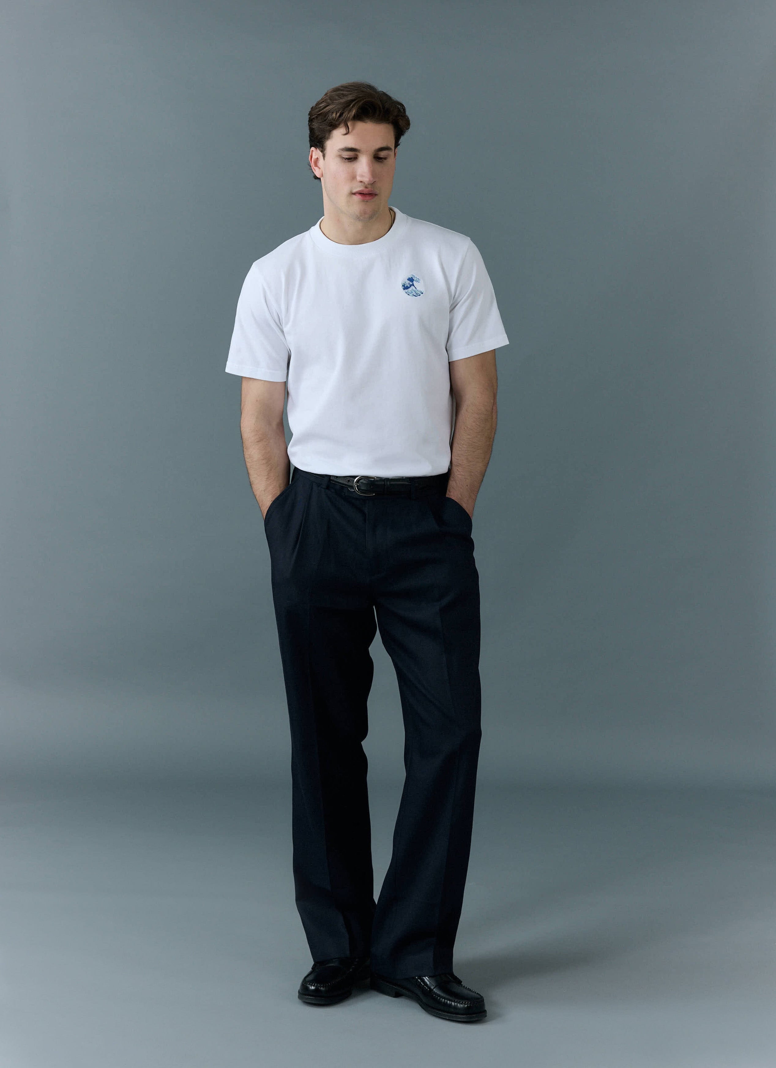 Percival Wave T Shirt in white, an embroidered organic cotton tee, styled on a model with black trousers and loafers.