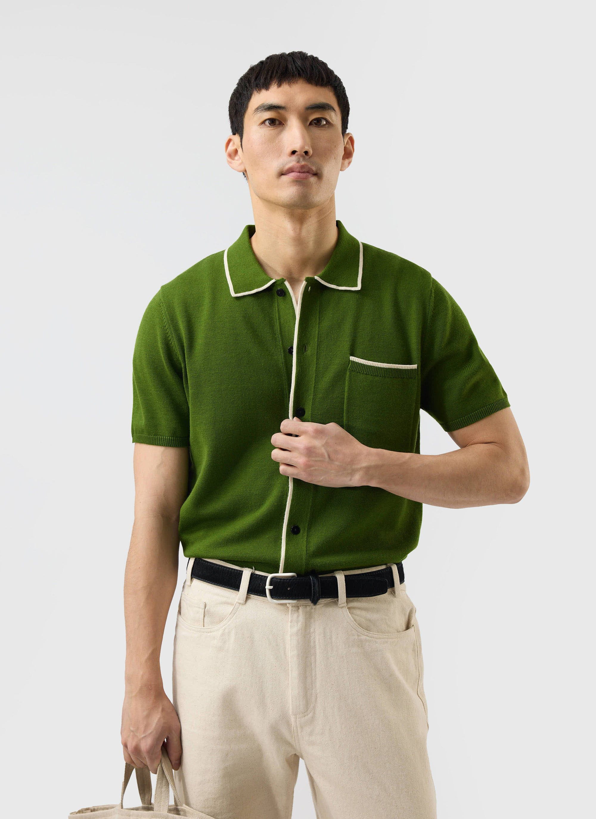 A model wears the Percival Contrast Trim Shirt in forest green, a wool-blend knit with ecru piping, on a white background.