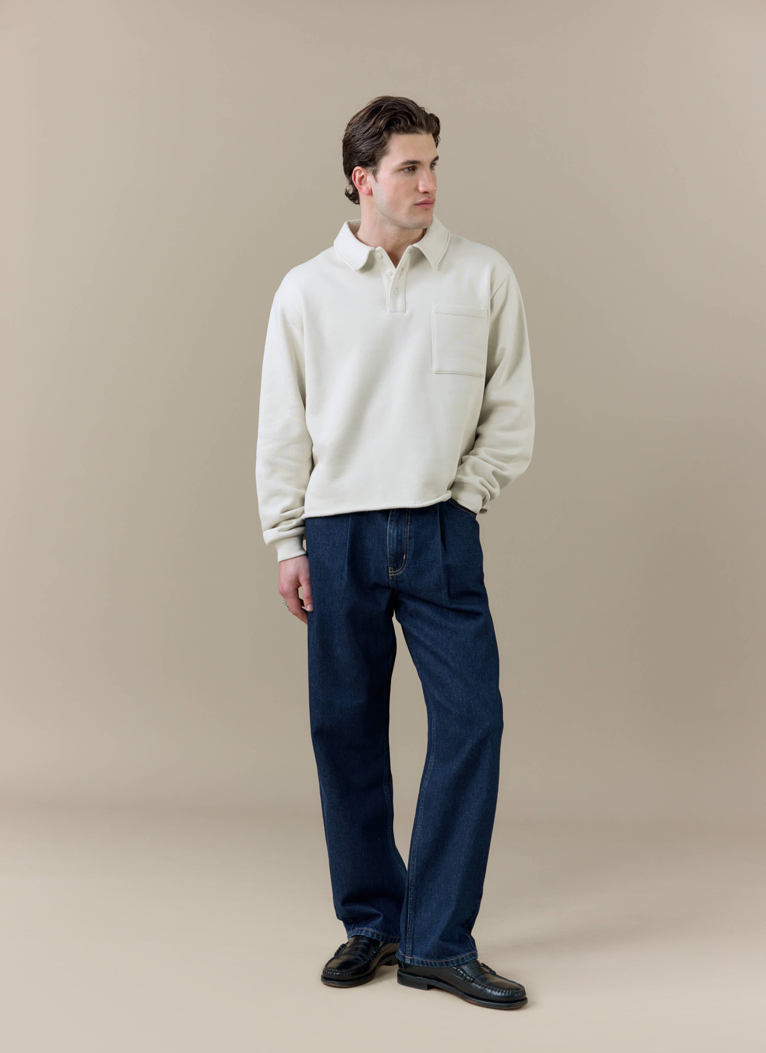 A model wearing the Percival Dudley Boxy Sweatshirt in ecru cream organic cotton, featuring a polo collar and boxy fit.