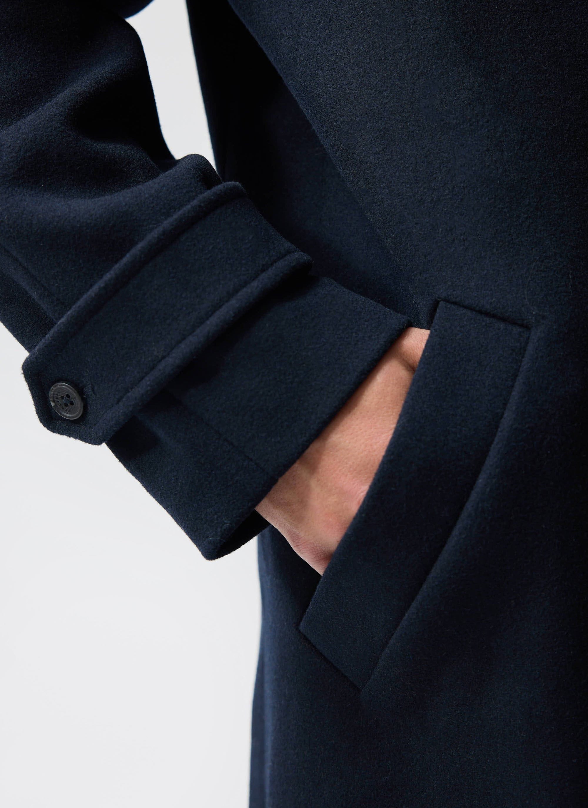 Close-up of the Percival Men's Wool Car Coat in navy, showing the cuff detail with branded button and side pocket.