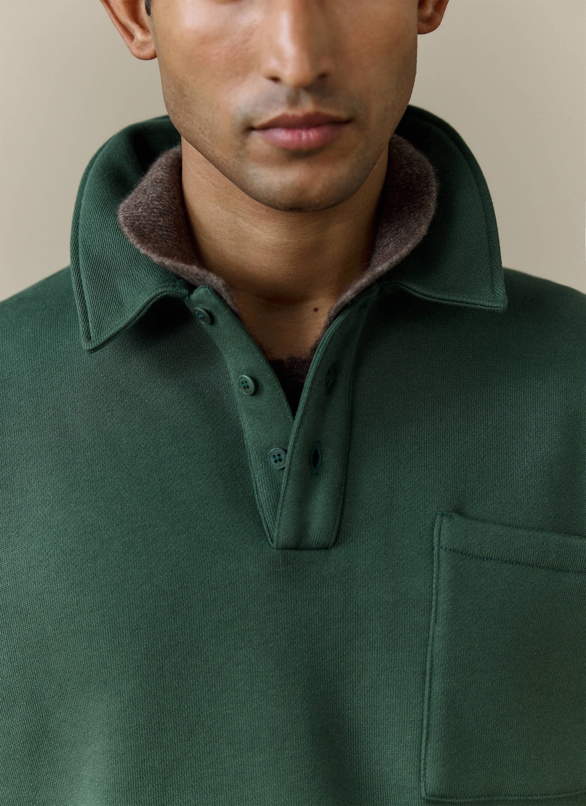 A close-up shot of the collar, button placket and chest pocket on the Percival Dudley Boxy Sweatshirt in Forest green.
