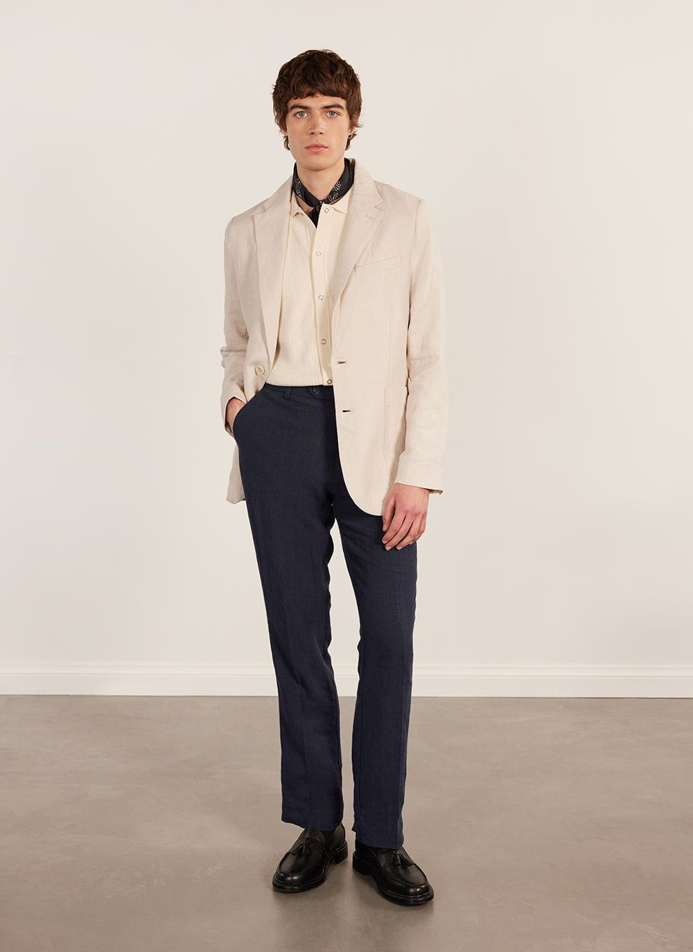 A model wears the Percival Pablo Cuban Shirt in cream, layered under a light blazer with dark trousers and black shoes.