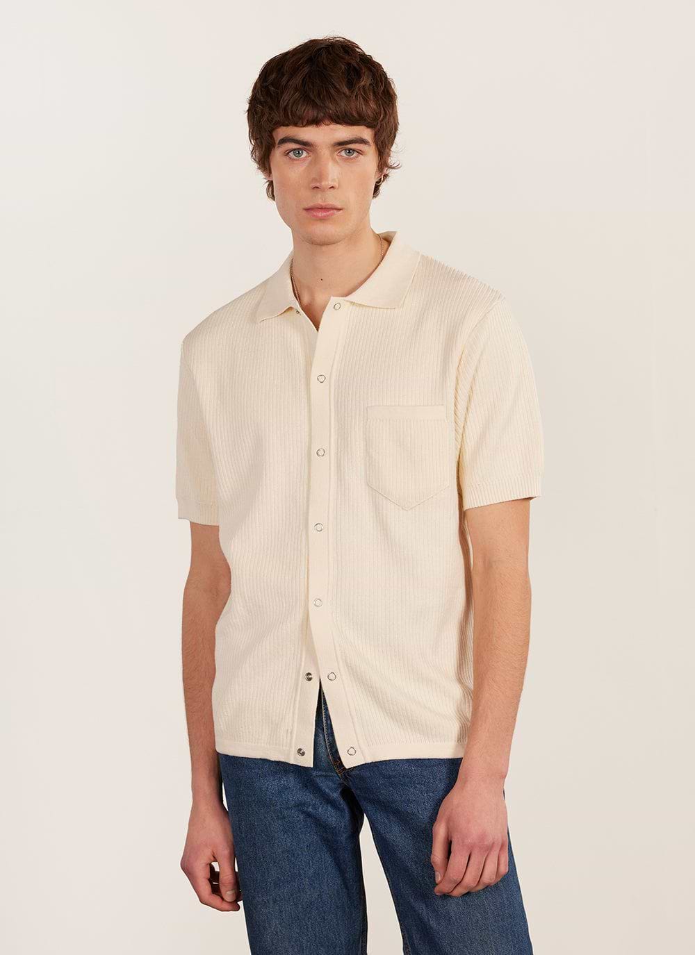 A model wears the Percival Pablo Cuban Shirt in cream, a knitted short-sleeve shirt with a chest pocket and popper buttons.