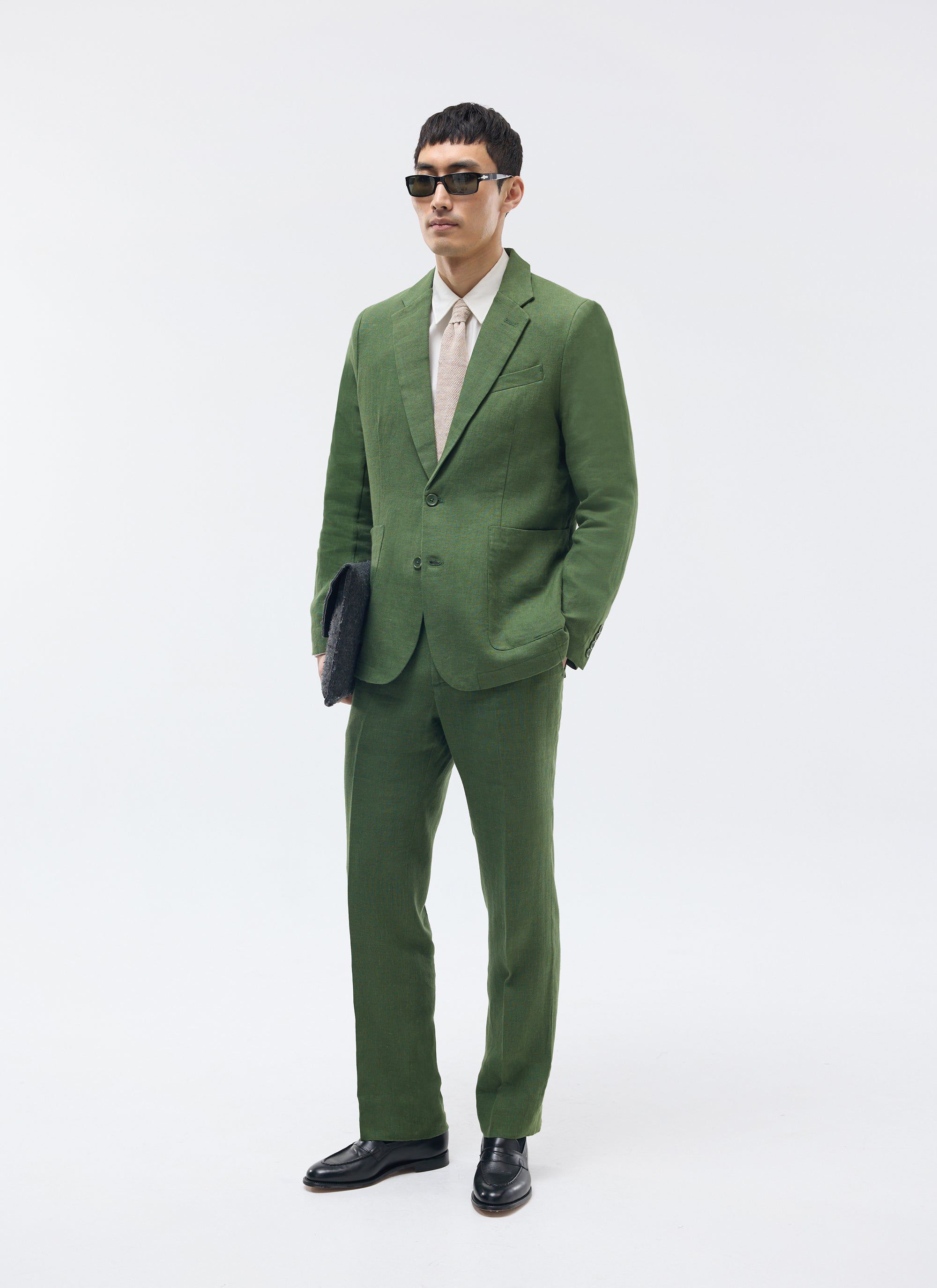 A model wears the Percival forest green linen blazer and matching trousers, styled with sunglasses and black loafers.