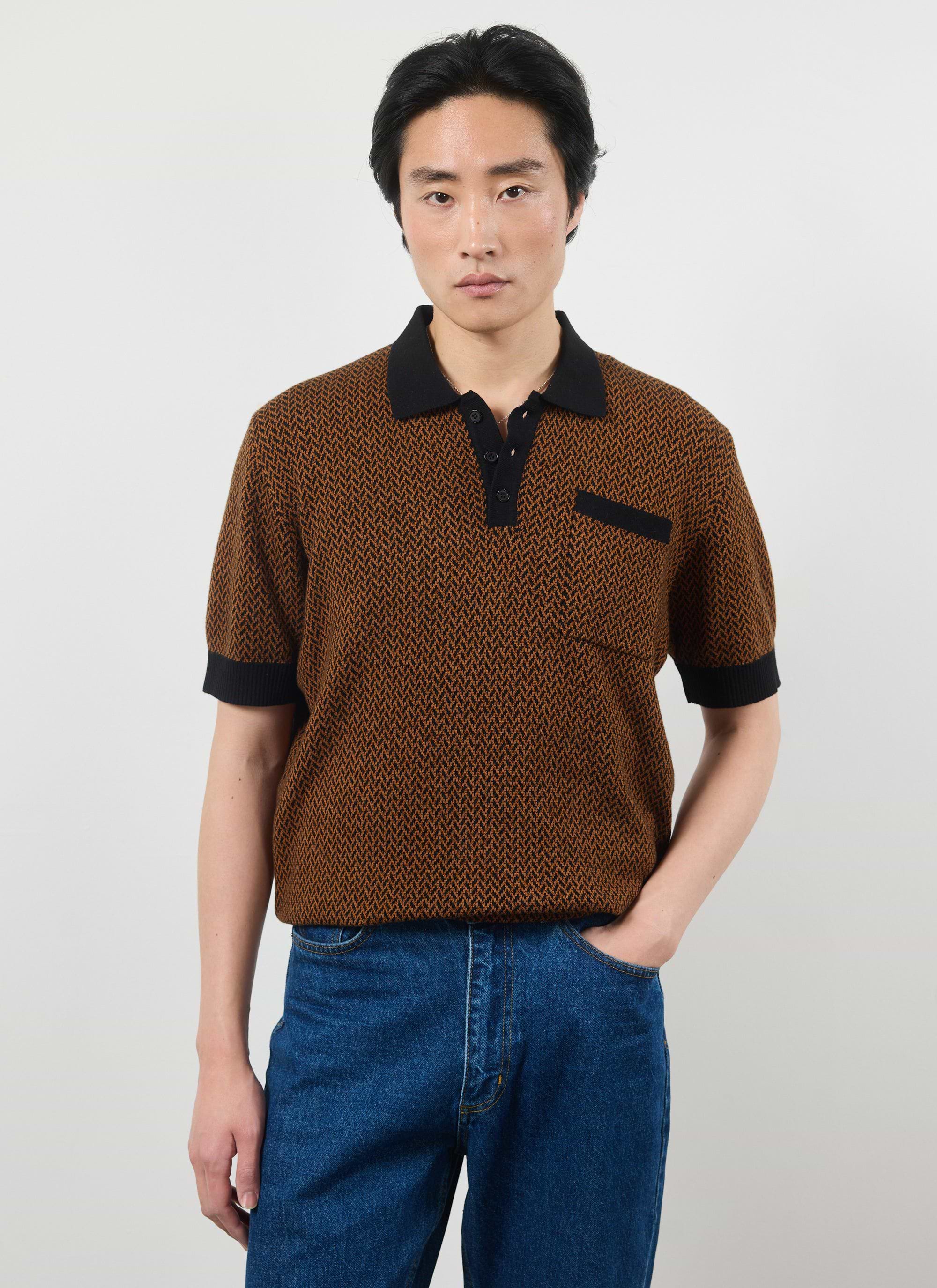 A model wears the Percival Casa Martini Knitted Polo in Espresso, a brown and black patterned short-sleeve shirt with jeans.