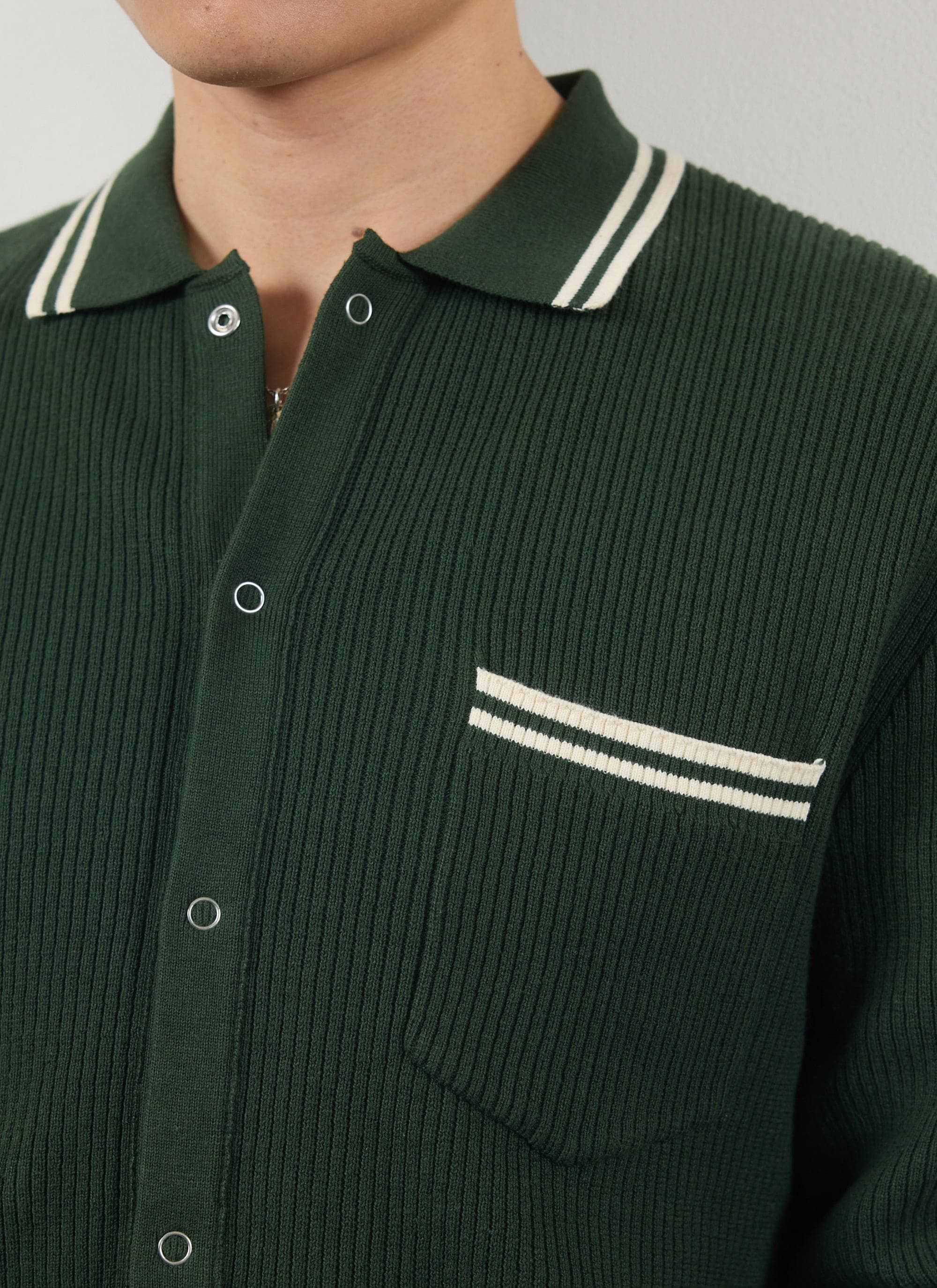 Close up of the Percival Pablo ribbed knitted shirt in forest green, showing the white striped collar and pocket.
