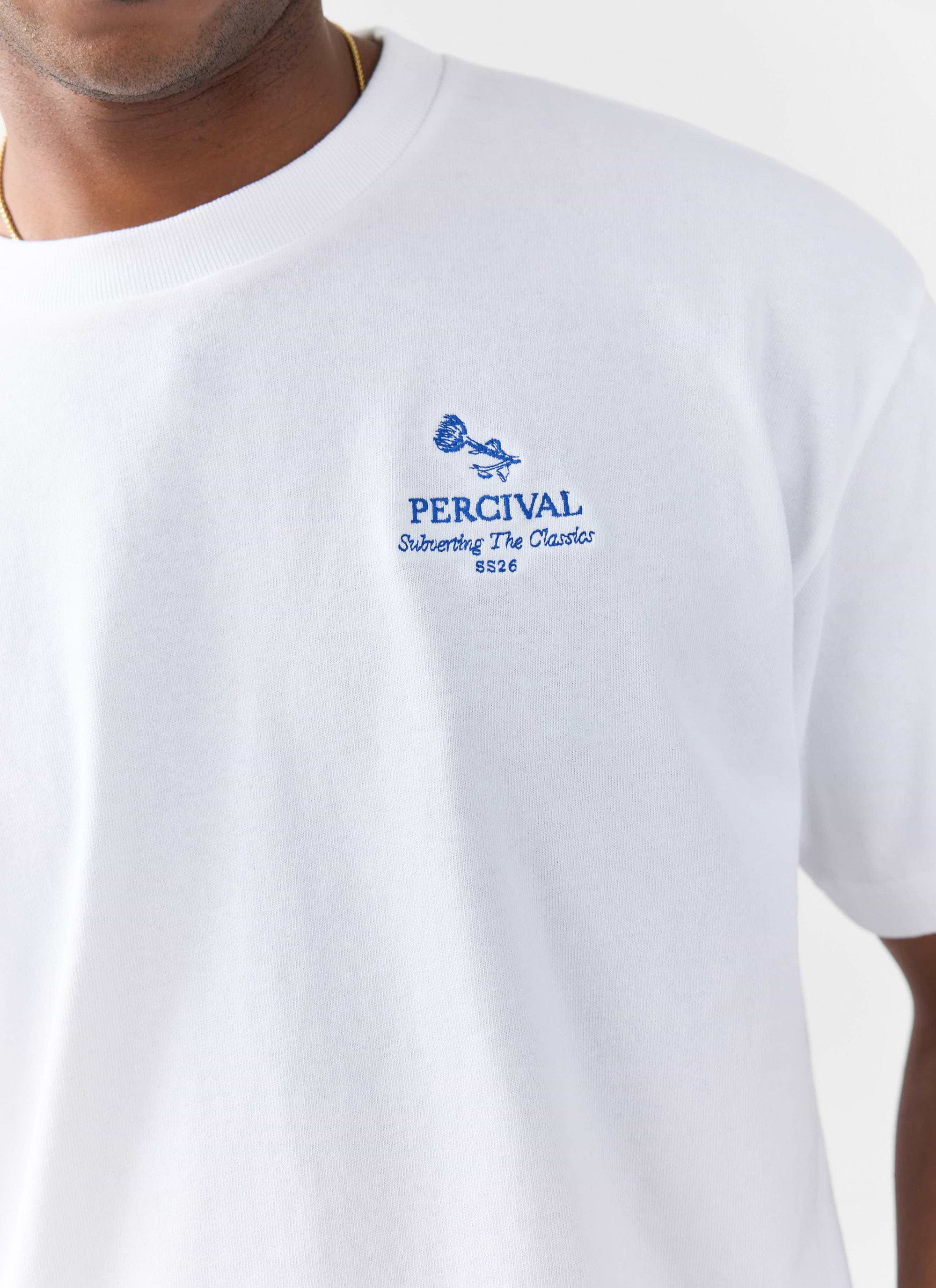 A close-up of the blue floral 'Subverting The Classics' embroidery on the chest of the white Percival Smith T-shirt.