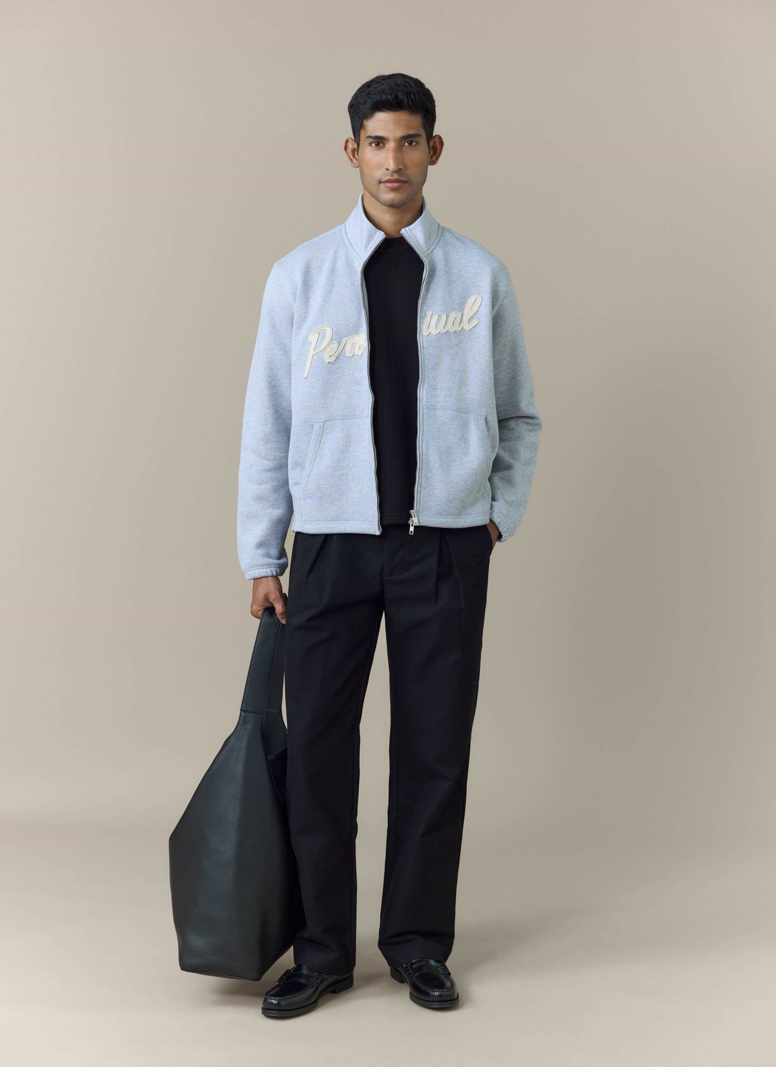 A model wears the Percival Curtis Boxy Zip Funnel Neck Sweatshirt in athletic grey, styled over a black top and trousers.