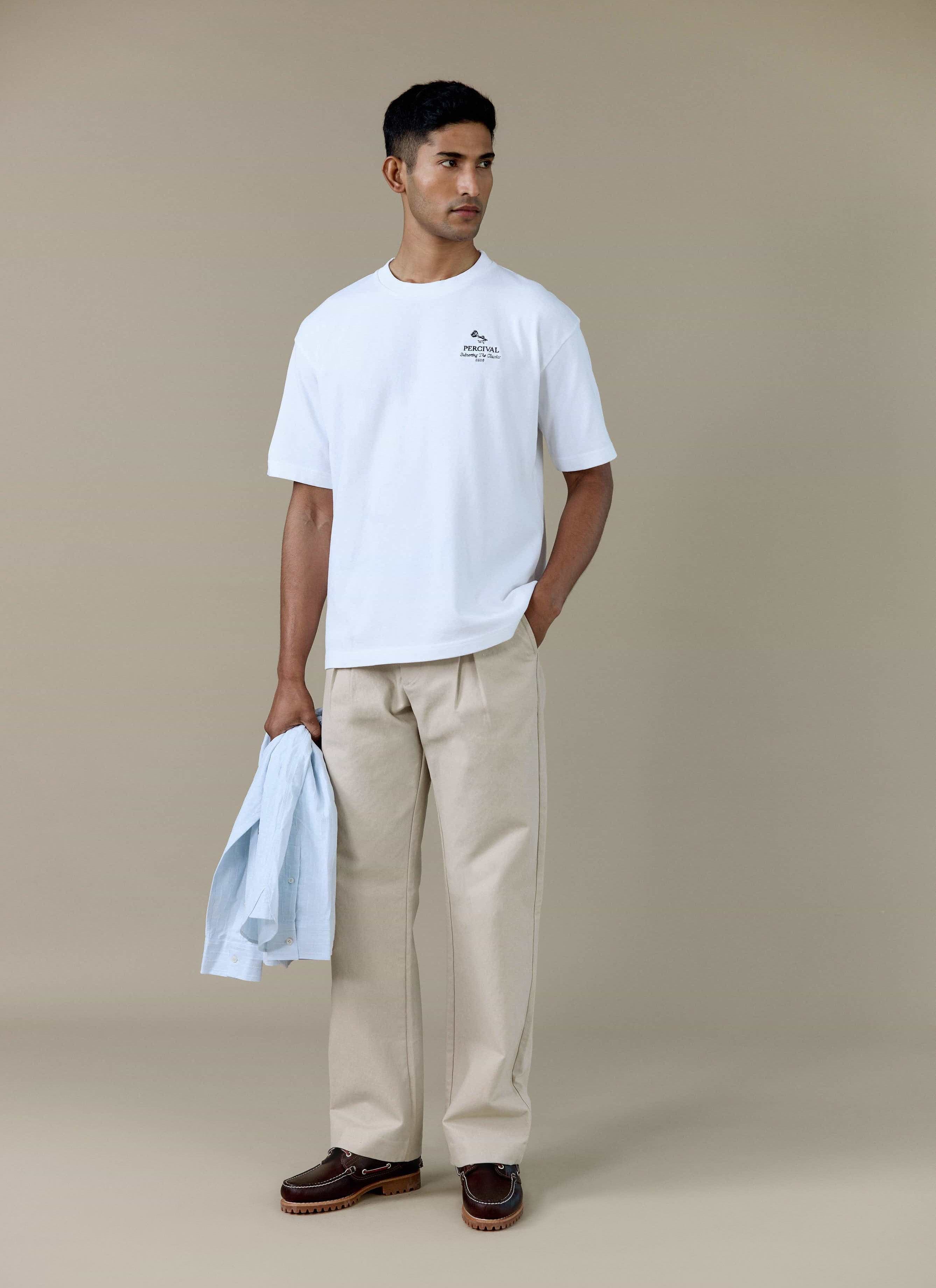 A model wearing the white Percival Perci Waters Oversized T Shirt in organic cotton, styled with beige trousers.