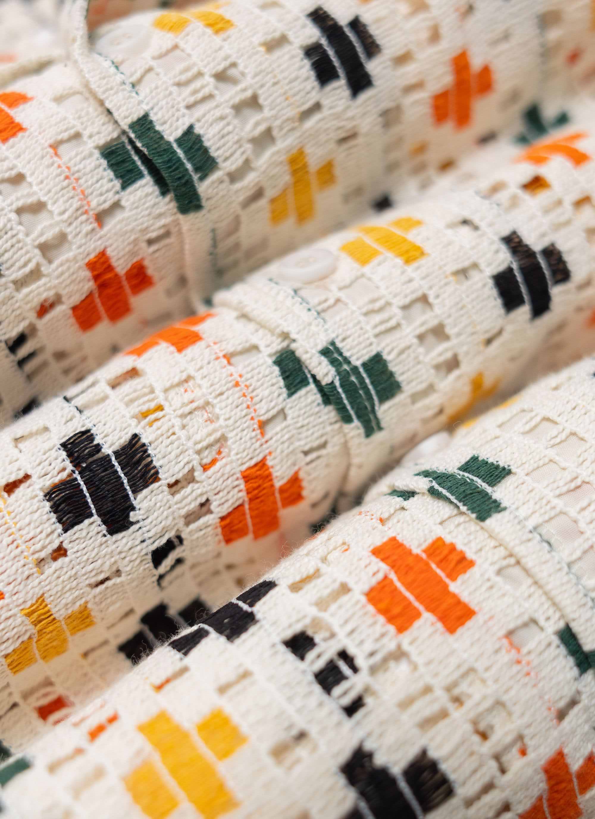 A close-up shot of the multi-coloured cross pattern on the ecru crochet fabric of the Percival Bailing Cuban Shirt.