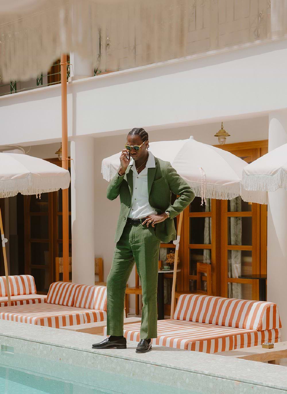Percival forest green tailored linen trousers and blazer on a model by a pool.