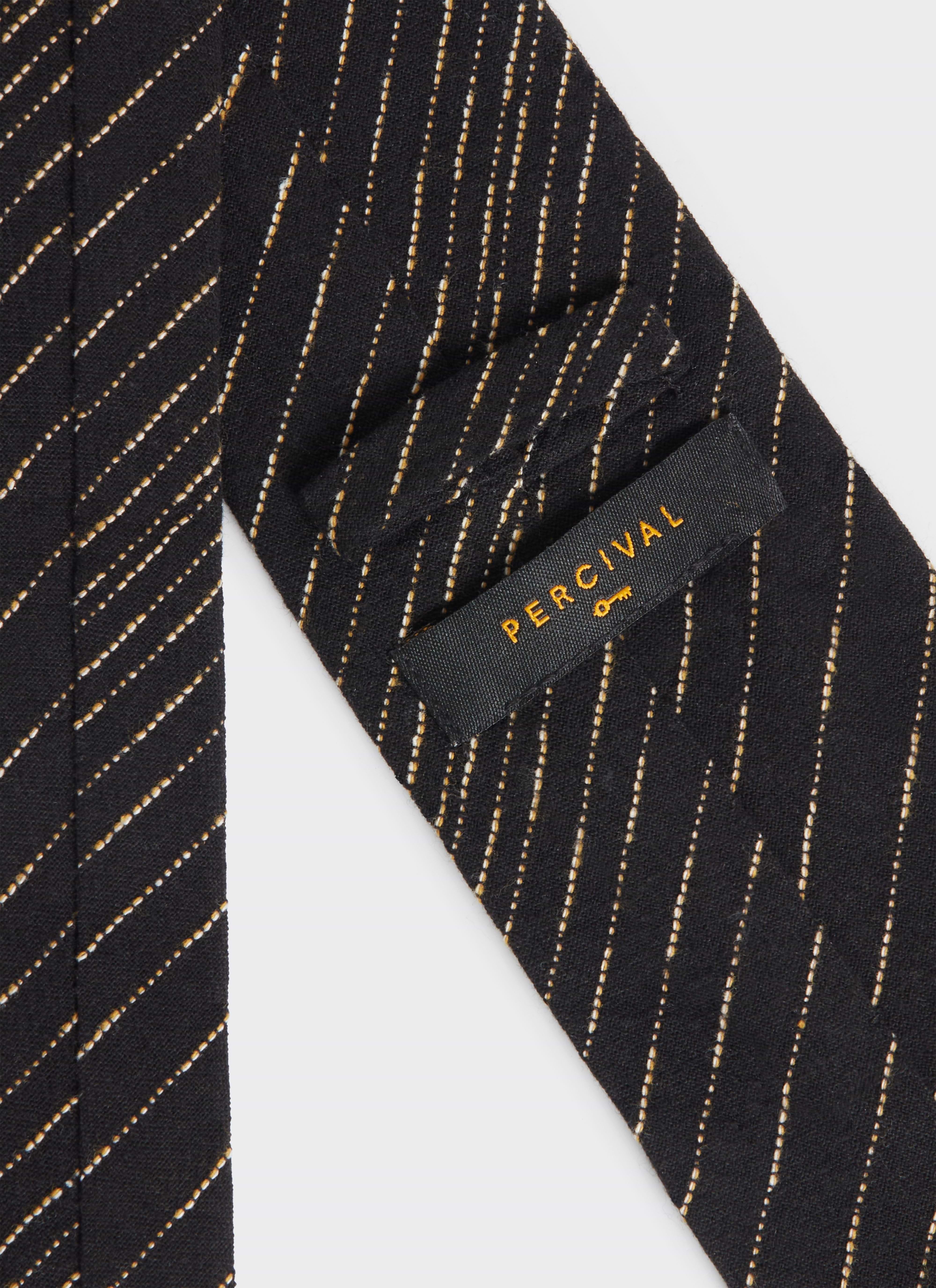 A close-up of the Percival label on the back of the black Leland Tie, showing the white dotted stripe pattern.