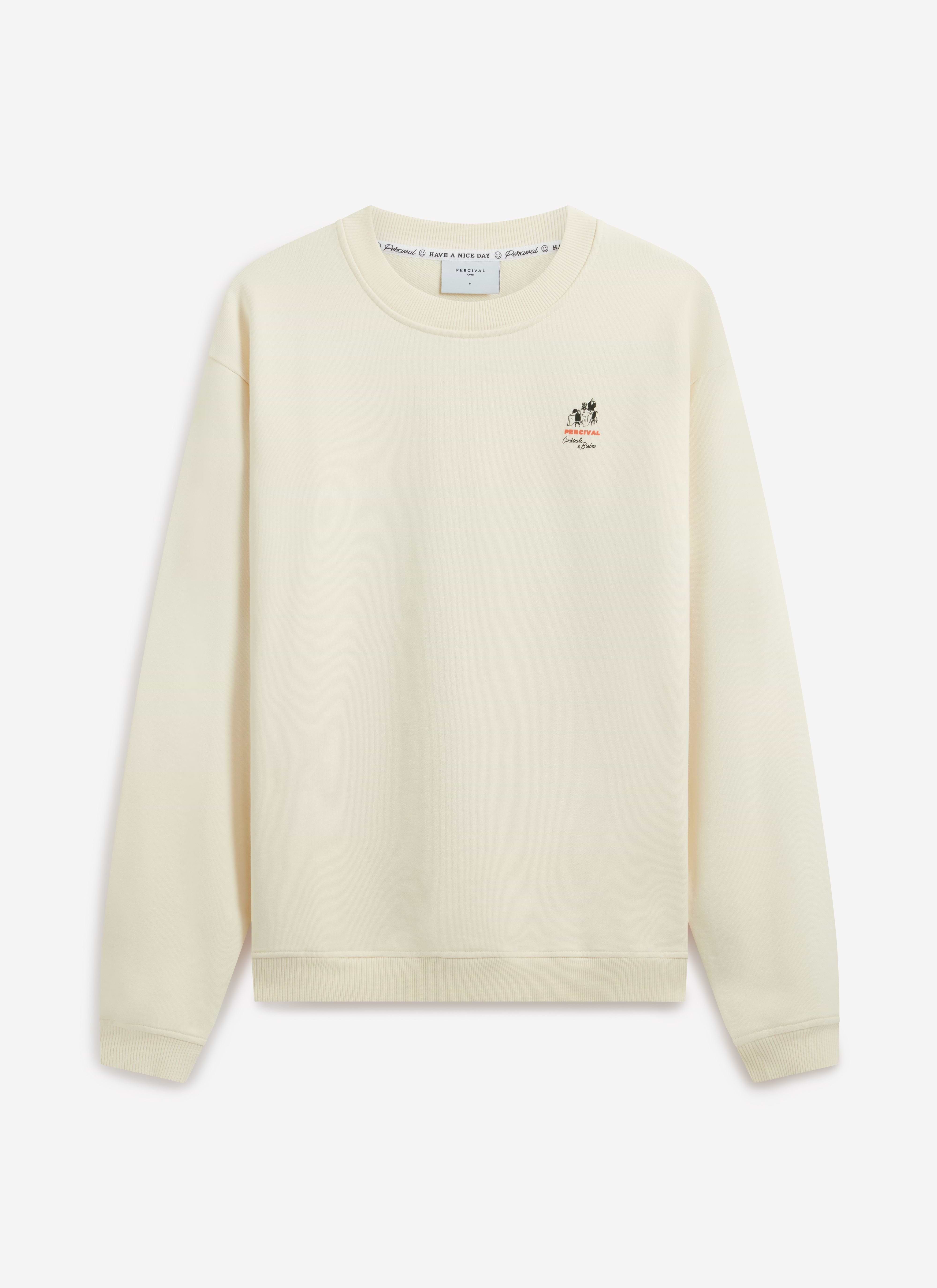 A model wears the Percival Bistro Printed Sweatshirt in ecru. Front-on studio shot showing the chest graphic and regular fit.