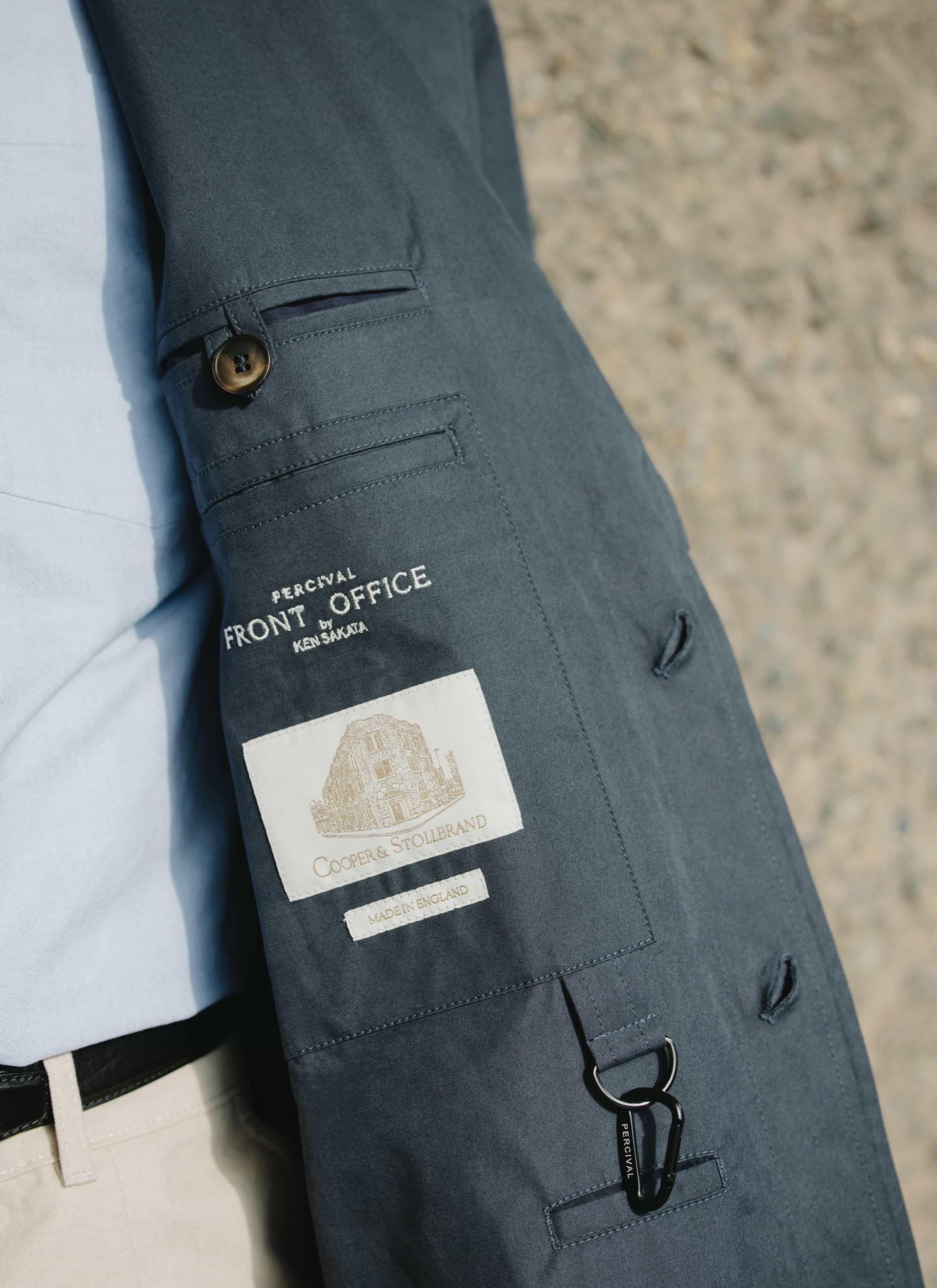 Detail of the navy Percival x Front Office Mac Coat, showing the internal labels, carabiner, and peached cotton finish.