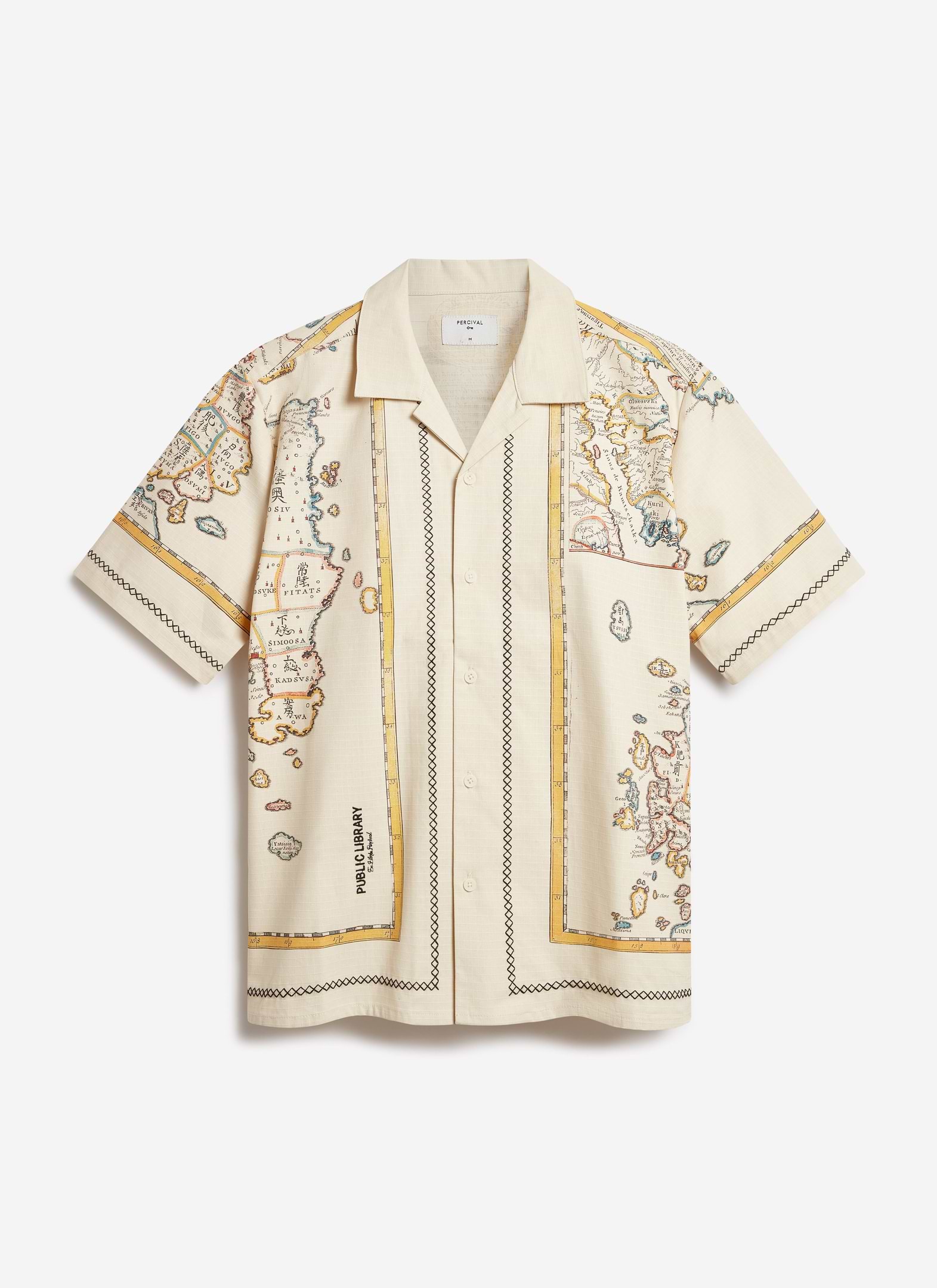 A flat lay of the Percival Ex Libris Cuban Shirt in ecru, showing its map-inspired artwork and black cross-stitch embroidery.