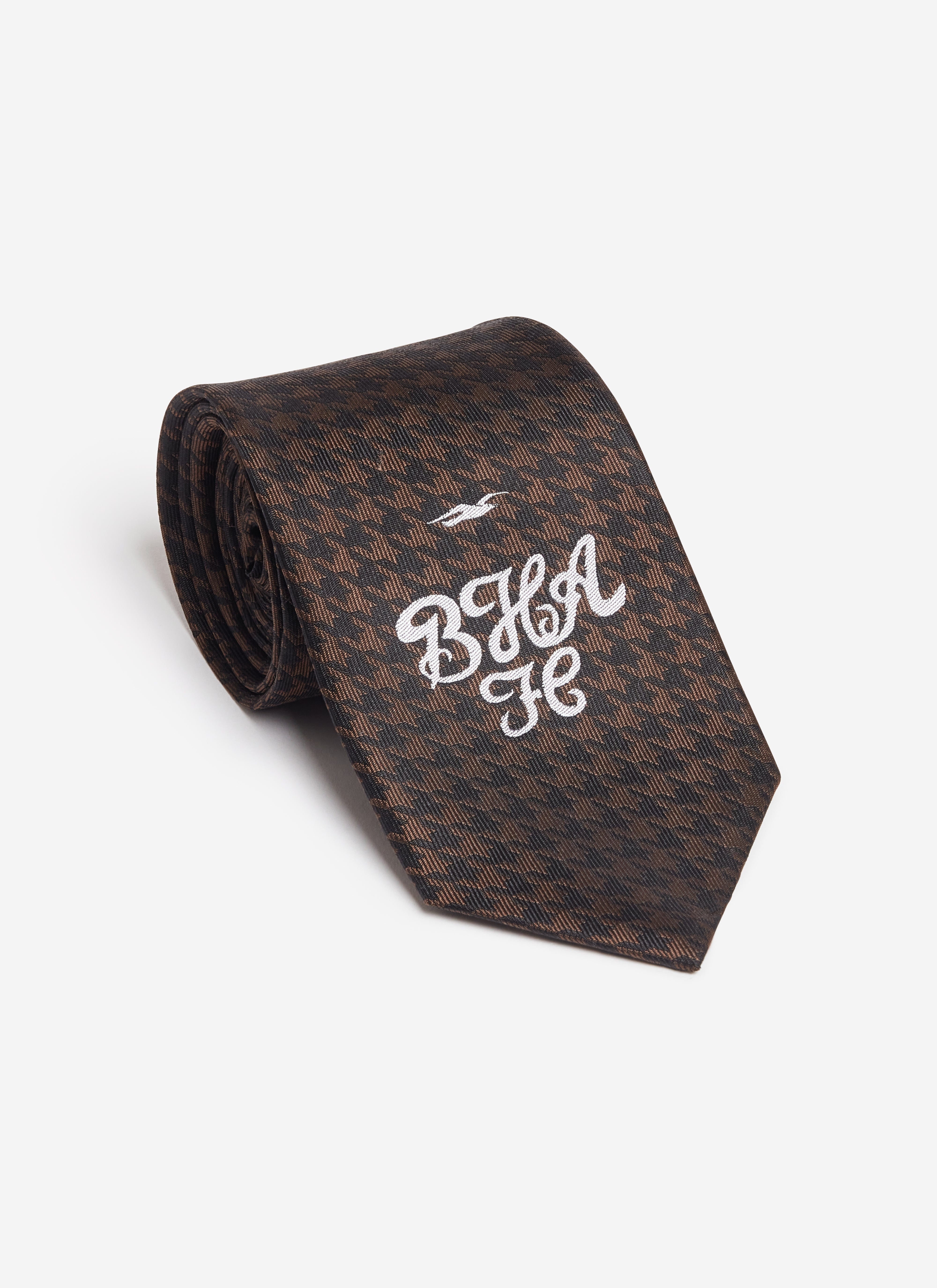 A rolled brown houndstooth silk tie from the Percival x Brighton & Hove Albion F.C. collection with white BHA FC embroidery.