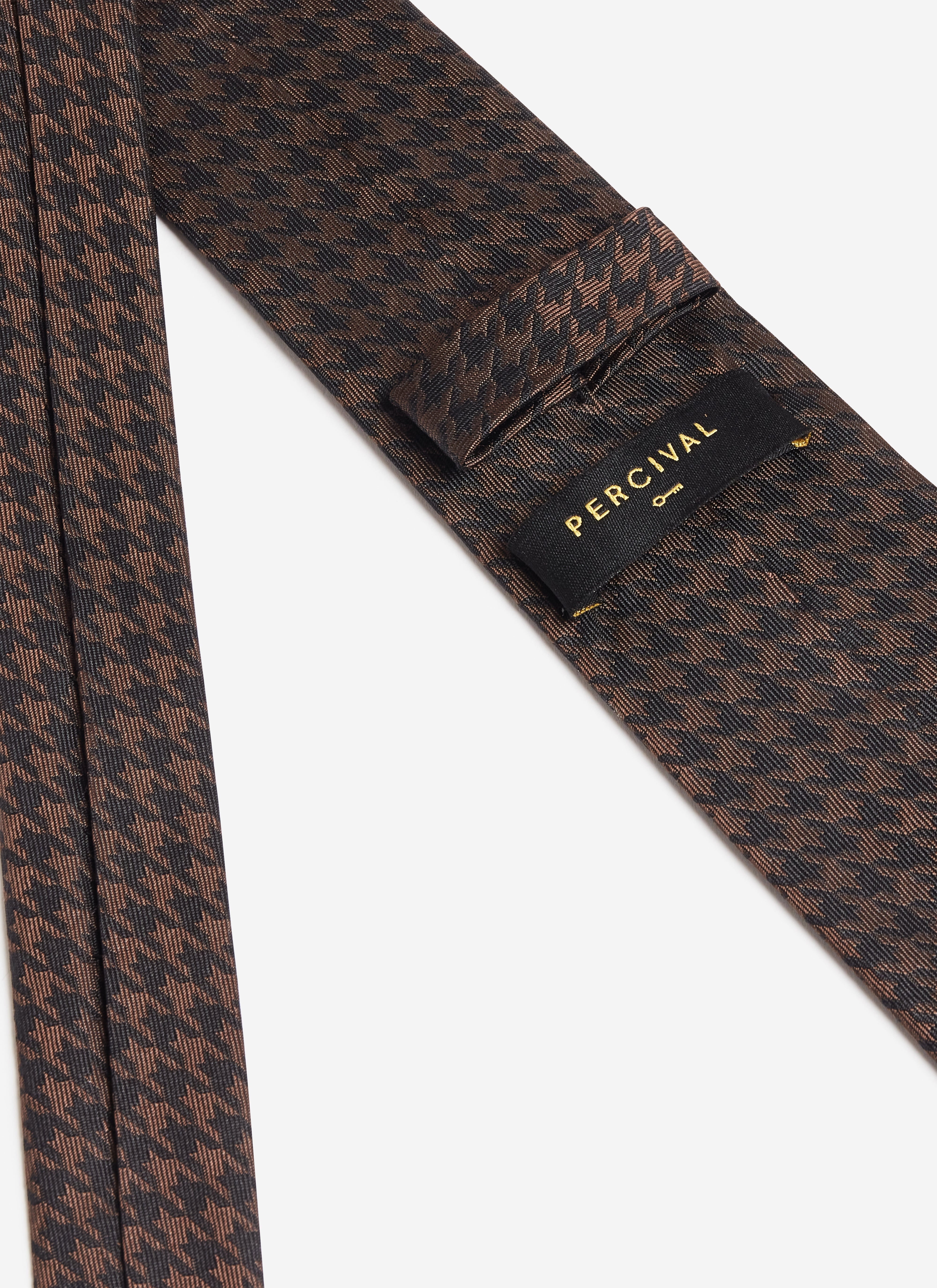 A close-up of the brand label on the back of the Percival brown houndstooth silk tie.
