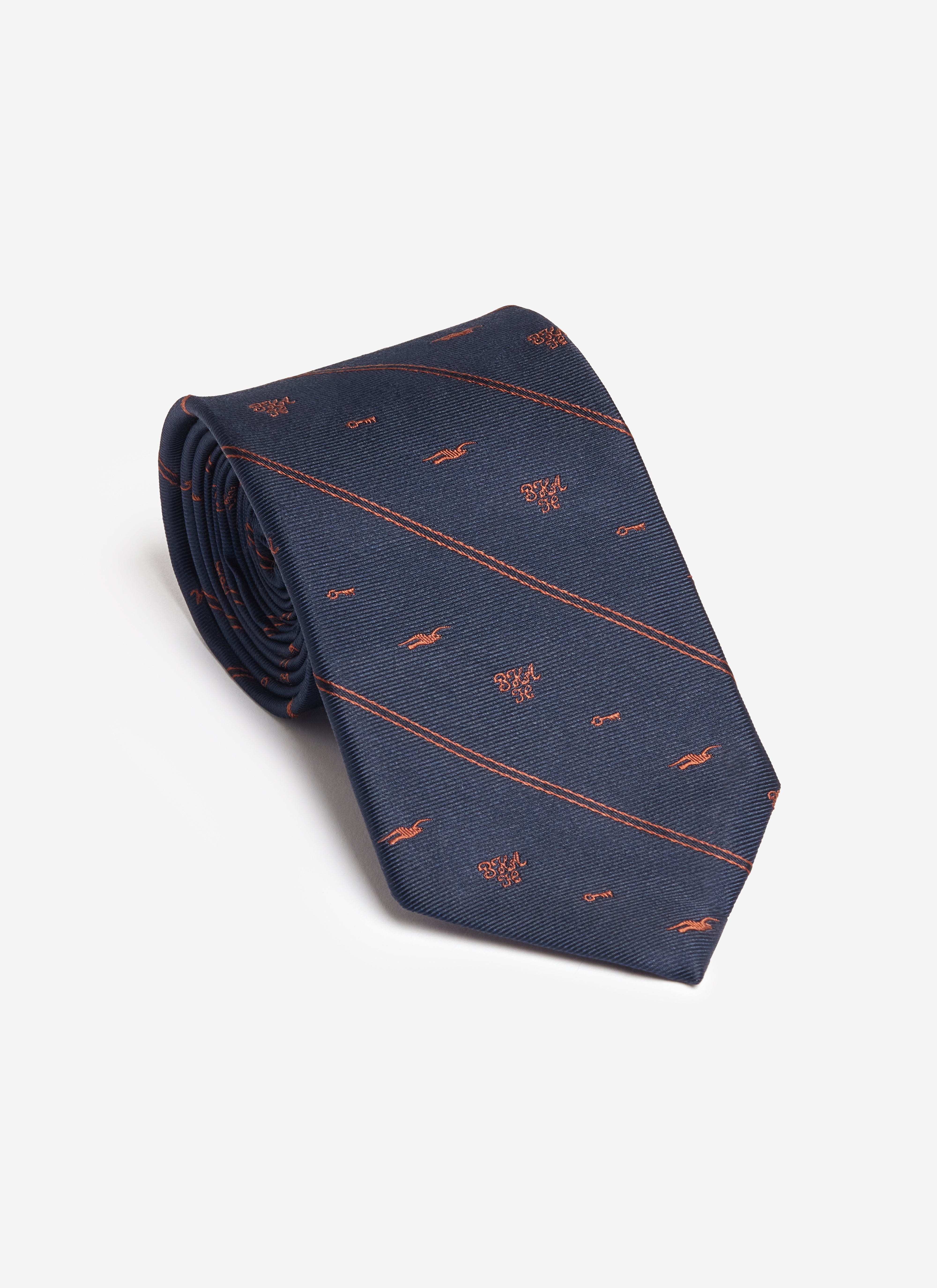 A rolled navy silk Jacquard Stripe Tie from the Percival x Brighton & Hove Albion F.C. collection with orange club motifs.
