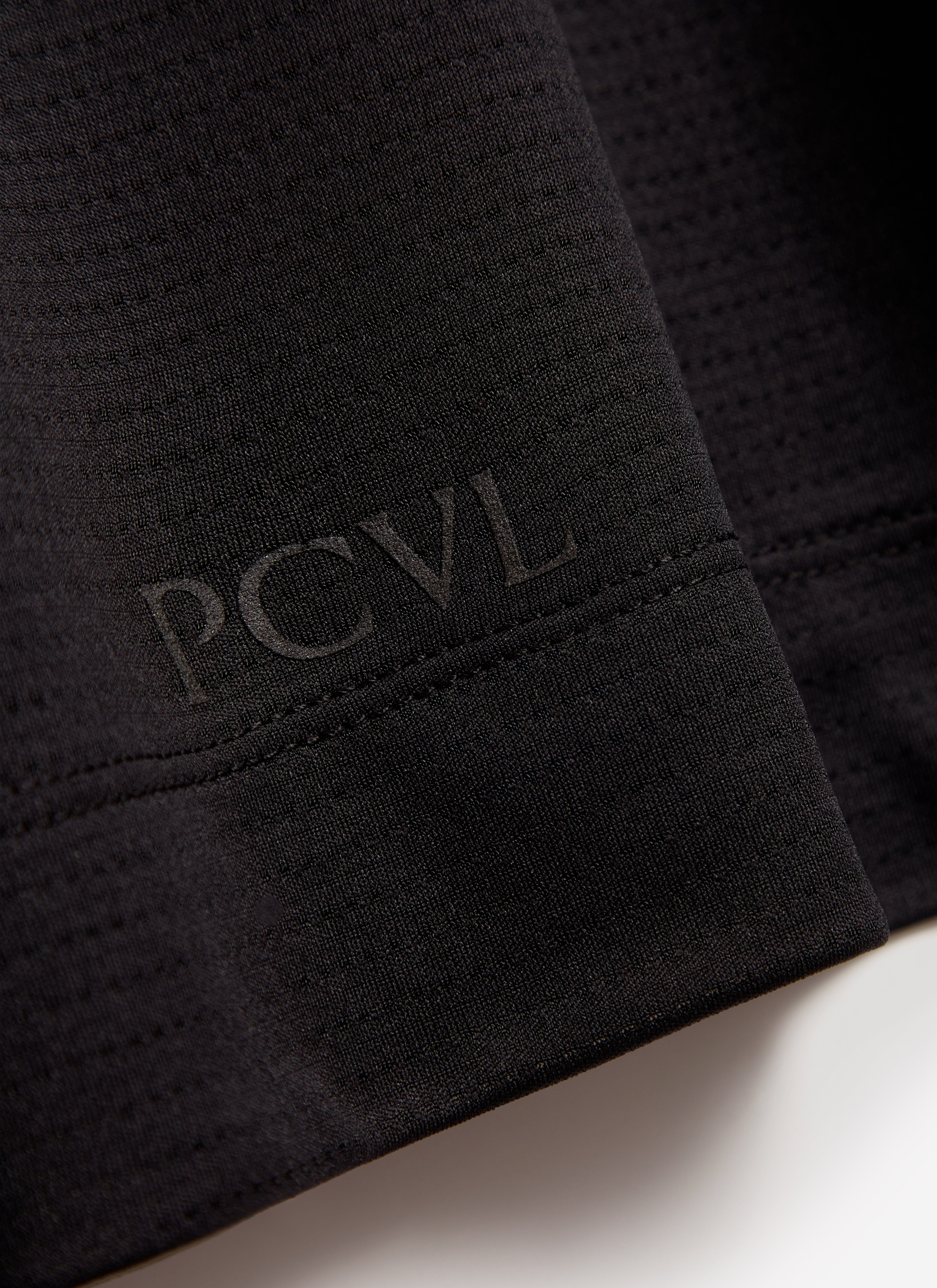 A close-up shot of the Percival PCVL Performance Top in black, detailing the tonal logo on the textured fabric.