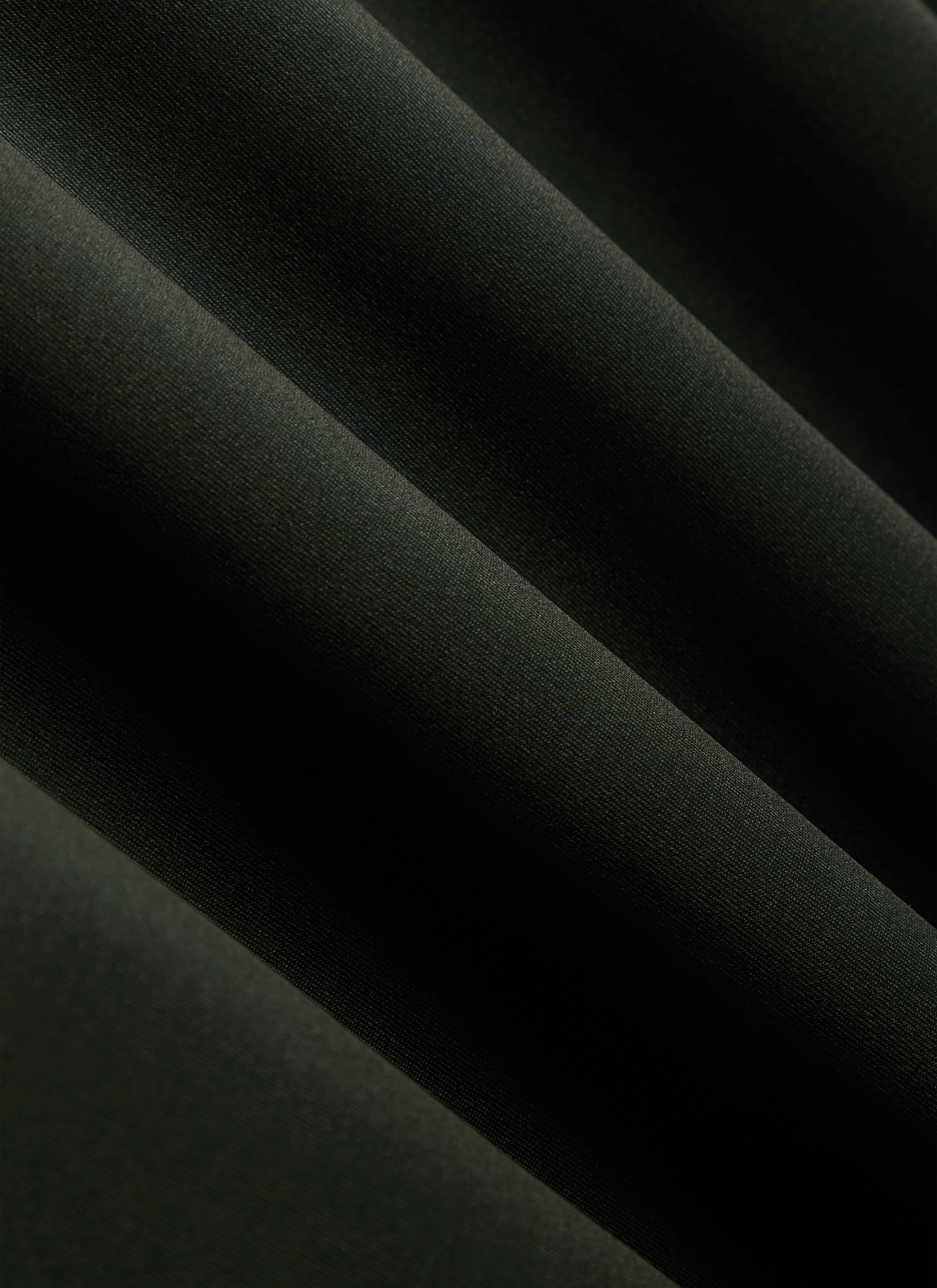 A detailed close-up shot of the forest green, moisture-wicking recycled fabric used in the Percival PCVL Performance Top.