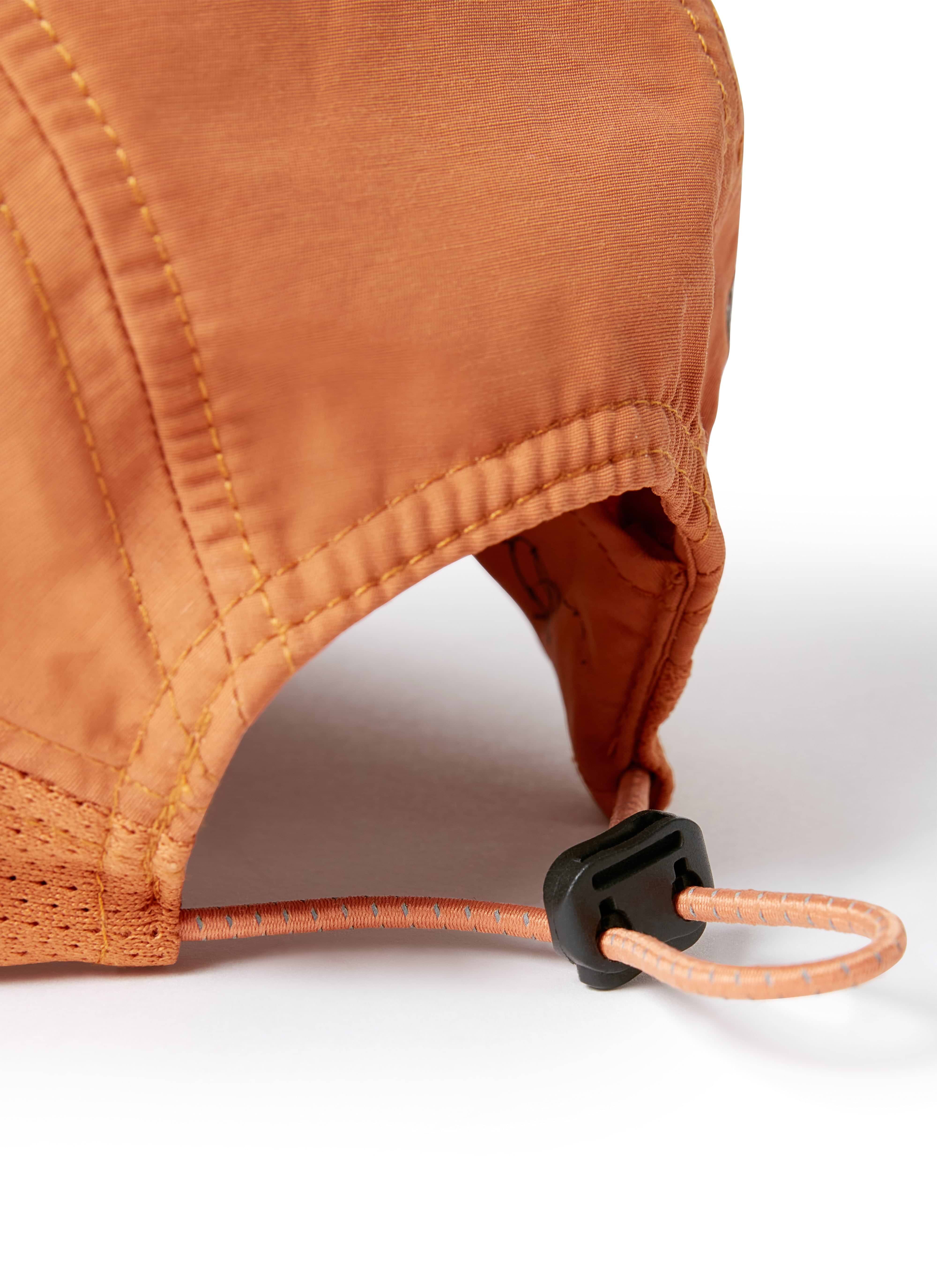 A close-up shot of the adjustable bungee cord fastening on the back of the PCVL Nylon Cap in rust by Percival.