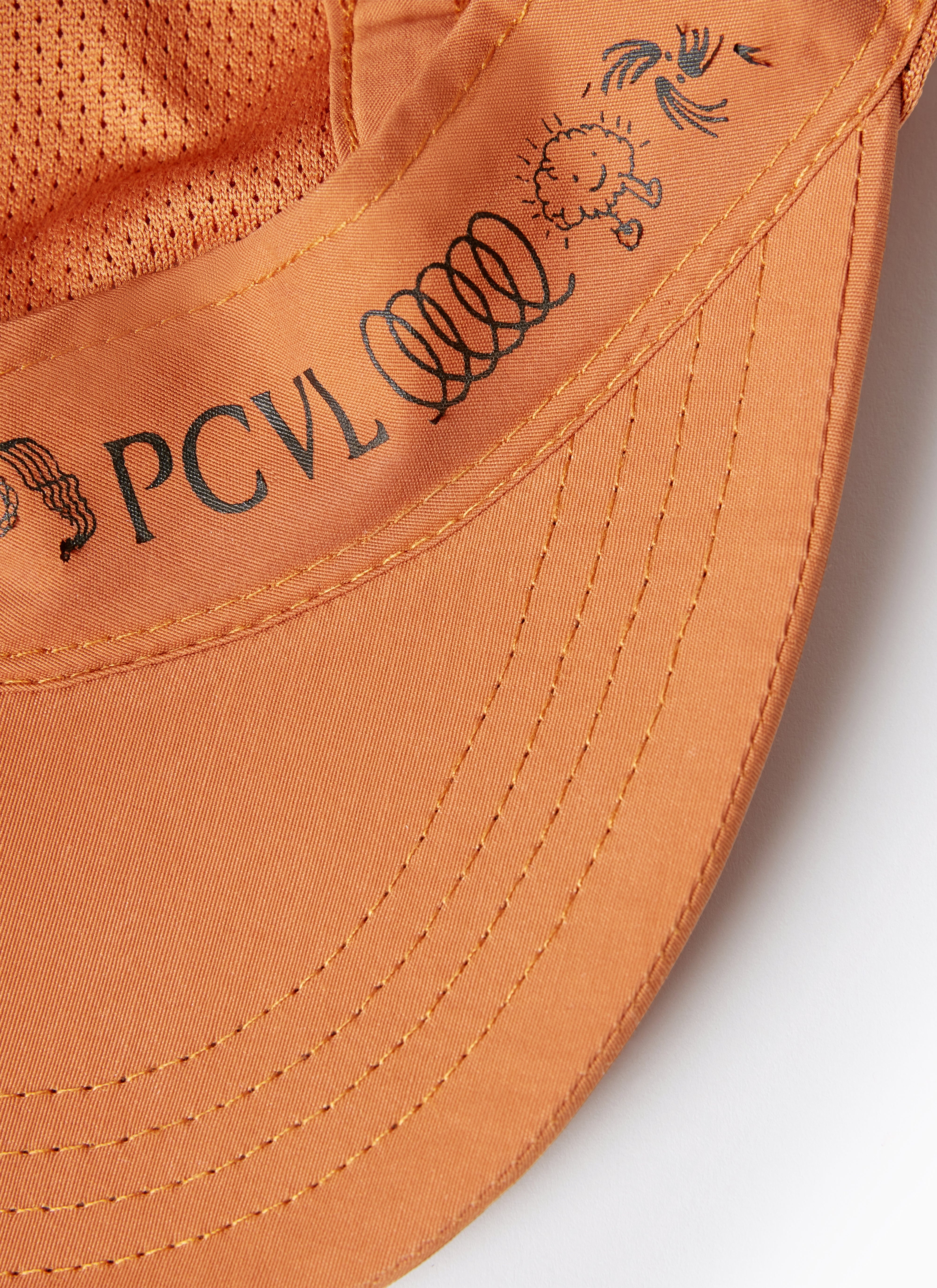 Detail shot of the Percival PCVL Nylon Cap in rust, highlighting the internal sweatband with its logo and graphic print.