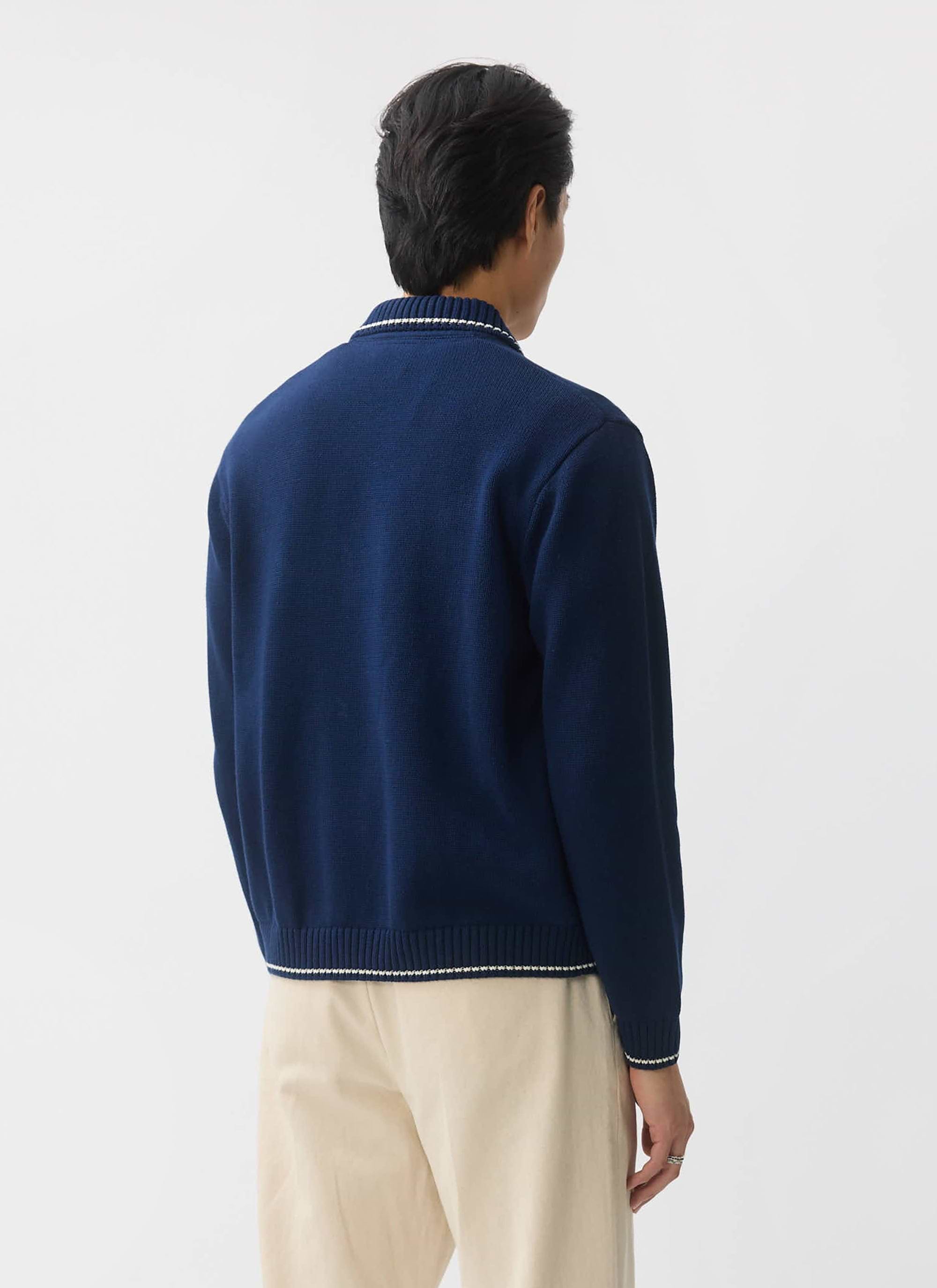 A model seen from behind wearing the Percival Gardner dense knit zip cardigan in navy with white contrast tipping.