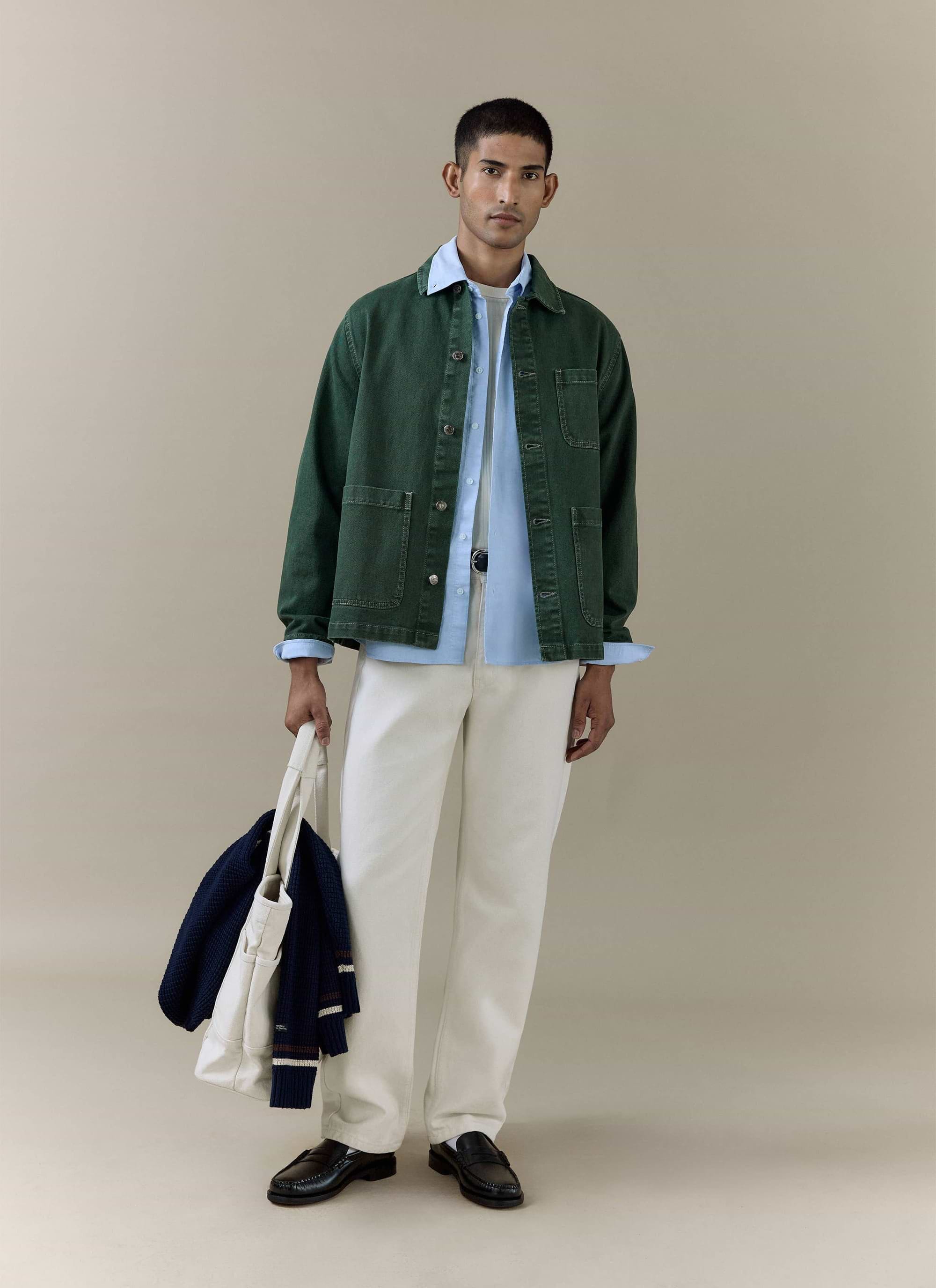 Model wearing the Percival Vintage Wash Oliver Chore Jacket in forest green cotton canvas with white trousers.
