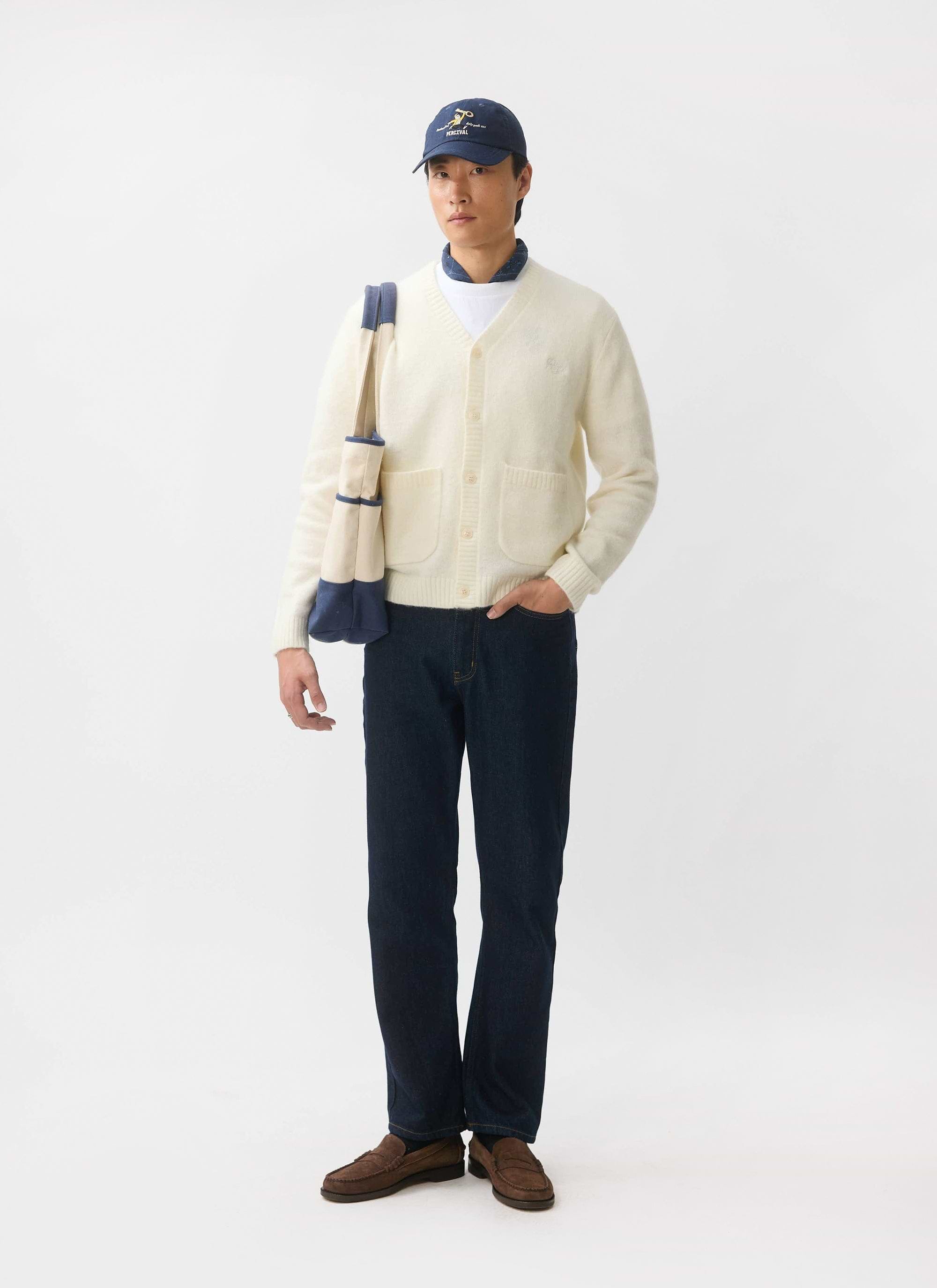 A model wears the Percival White Glove mohair cardigan in ecru, styled with dark jeans, a cap and a tote bag.