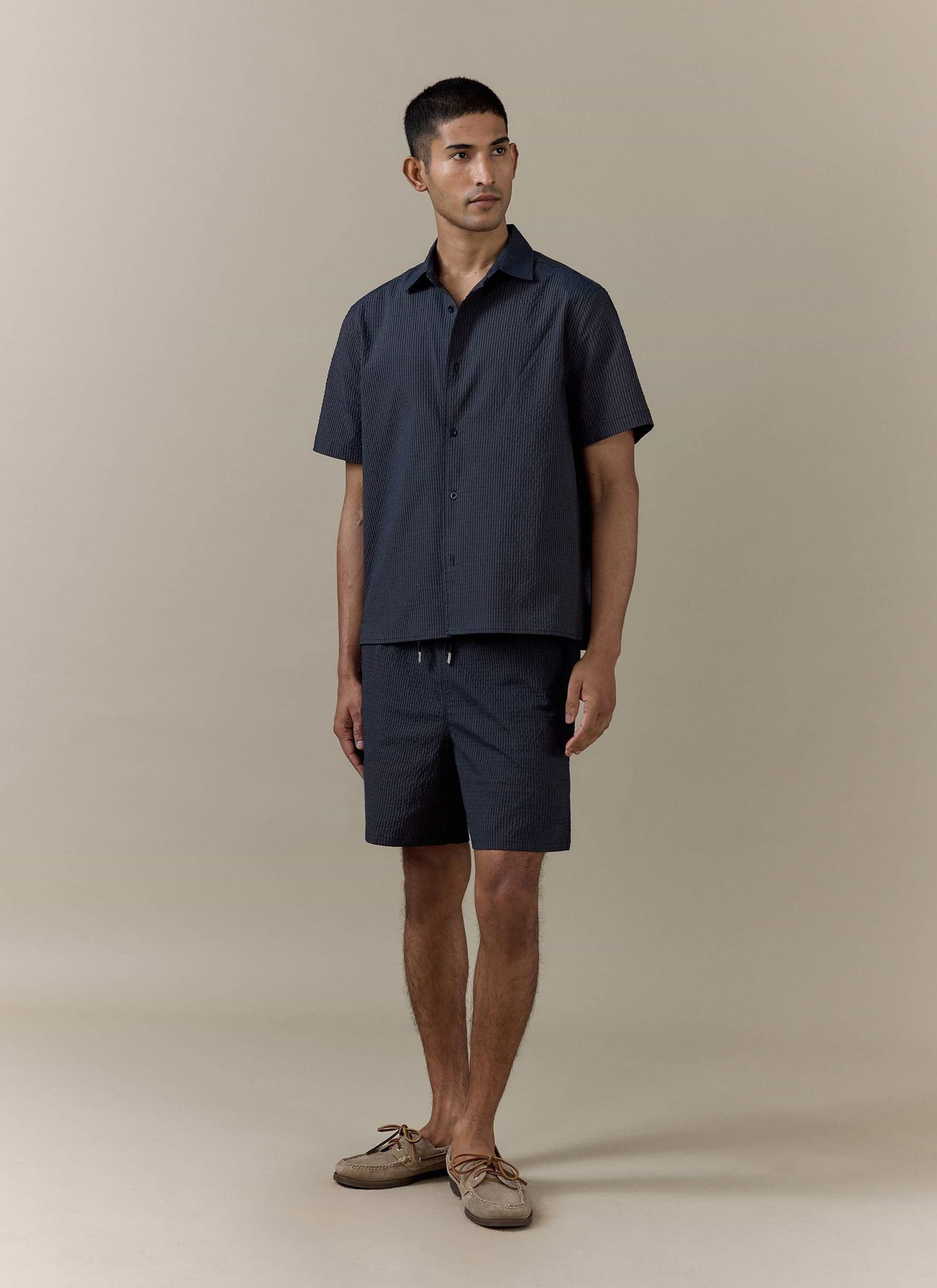 Navy stripe Rowan Seersucker Swim Shorts by Percival, styled as a matching set with a short-sleeved shirt.