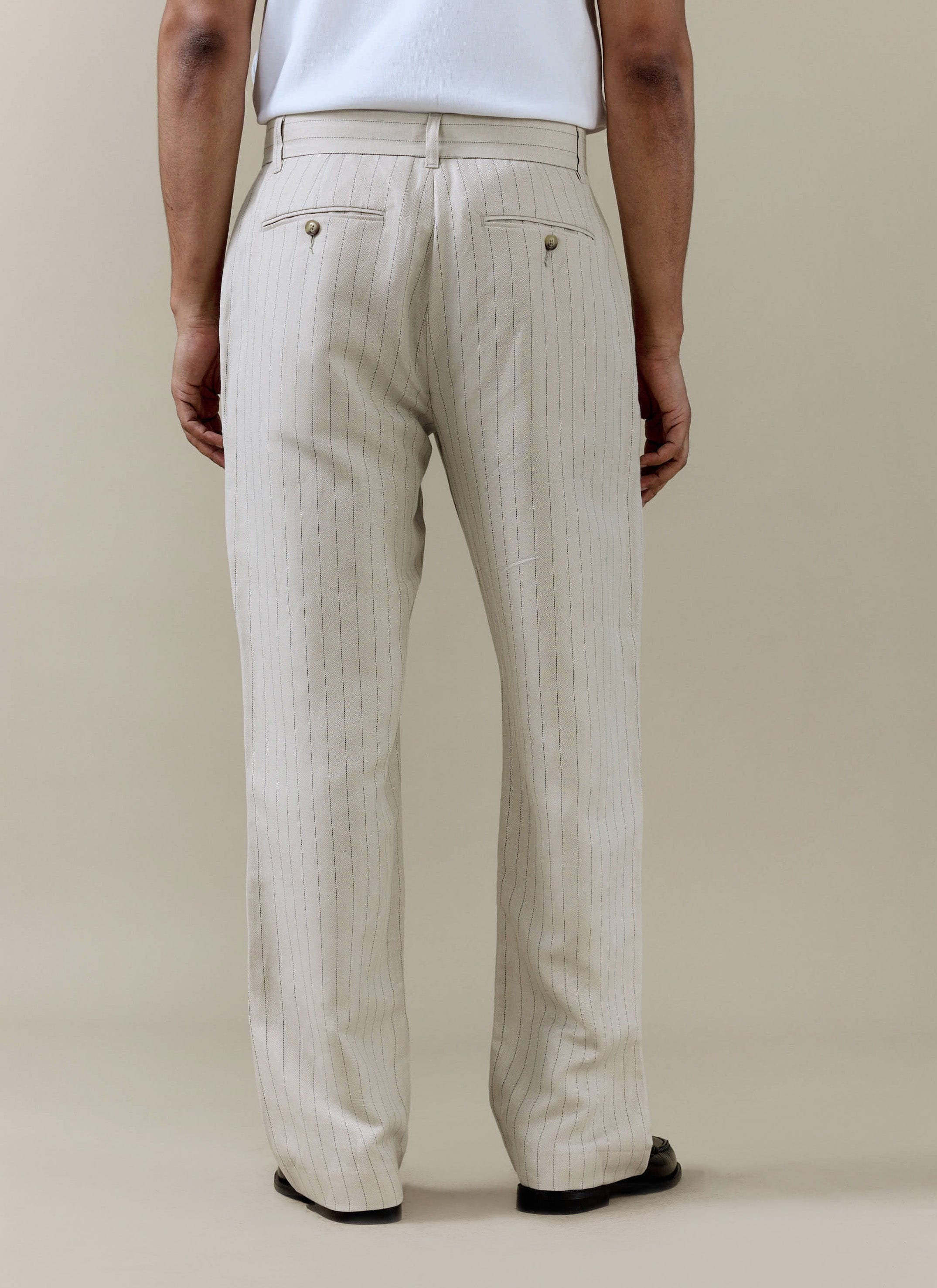 Back view of the Percival cream pinstripe pleated trousers in a linen blend, featuring back buttoned pockets.